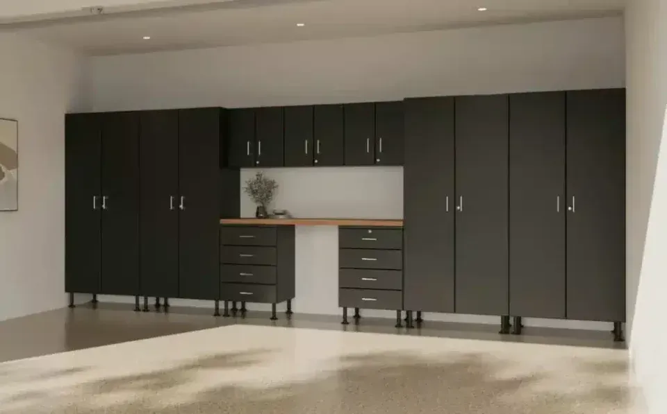 Modern room with black storage cabinets and drawers along a white wall, minimal decor and light wood floor