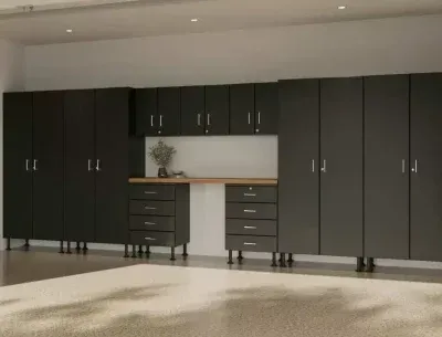 Modern garage with dark cabinets, built-in workbench, and overhead lighting.