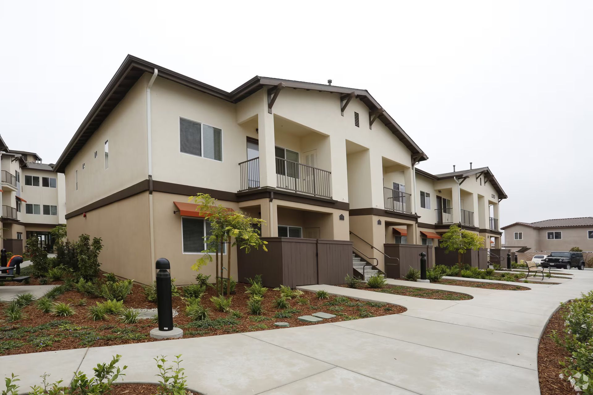 Row of beige townhouses with balconies and landscaped walkways in a residential complex