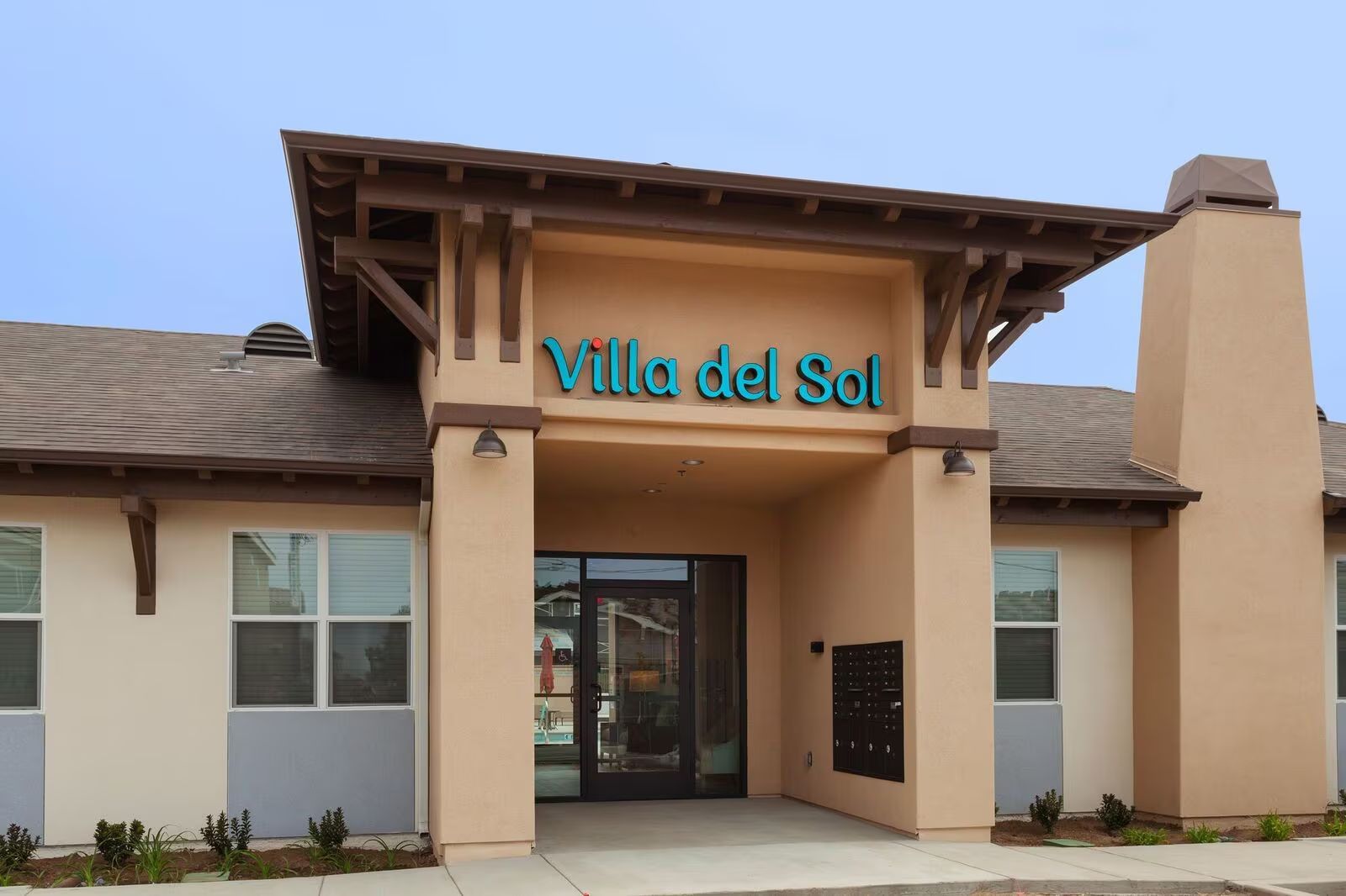 Entrance of Villa del Sol building with beige stucco walls and a covered entryway