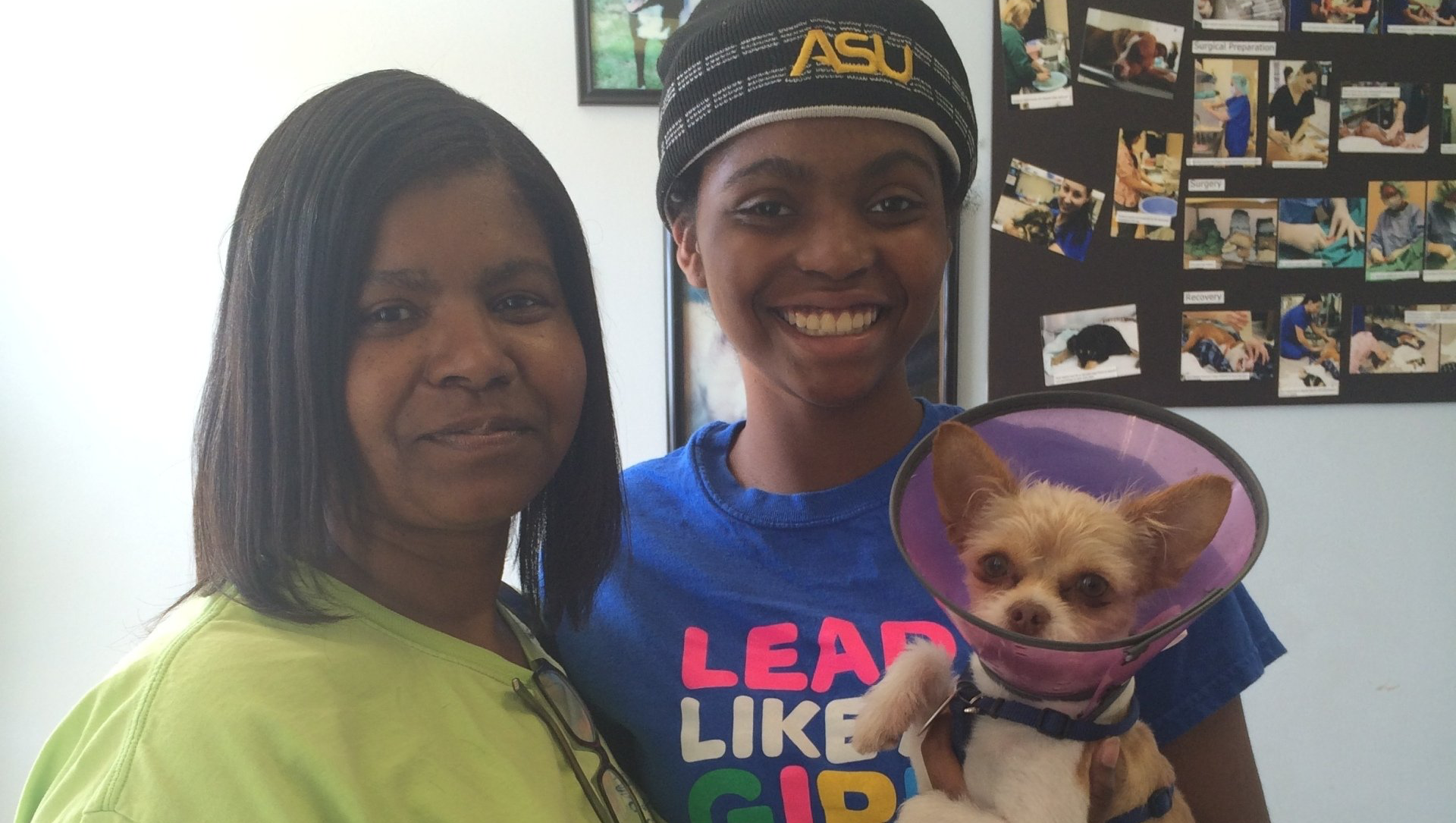 A woman wearing a blue shirt that says leap like a girl holds a small dog