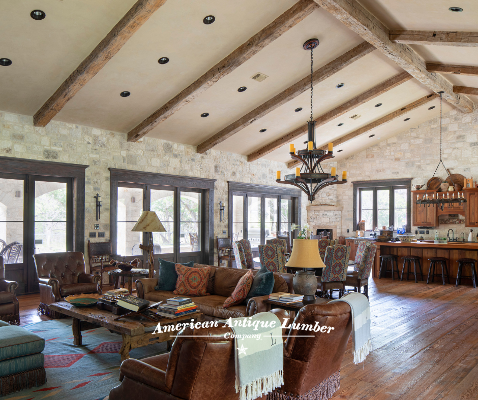 Living room with wood floors, stone walls, white wall vaulted ceiling with reclaimed beams. 