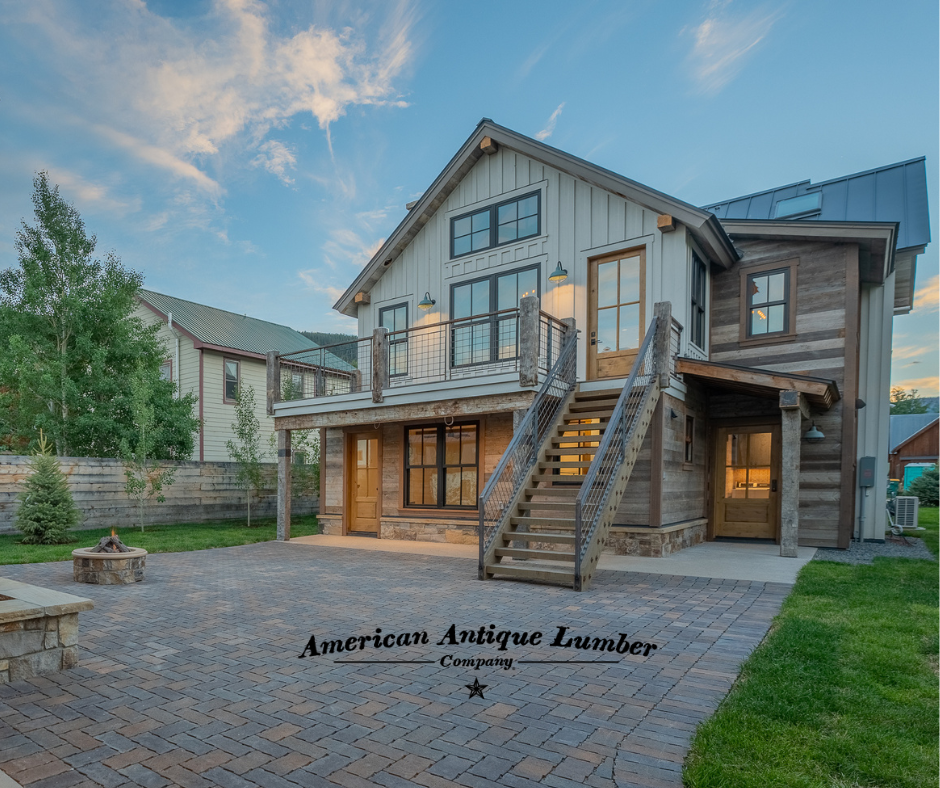 Back porch with stone patio and stone fireplace at dusk with light clouds. 