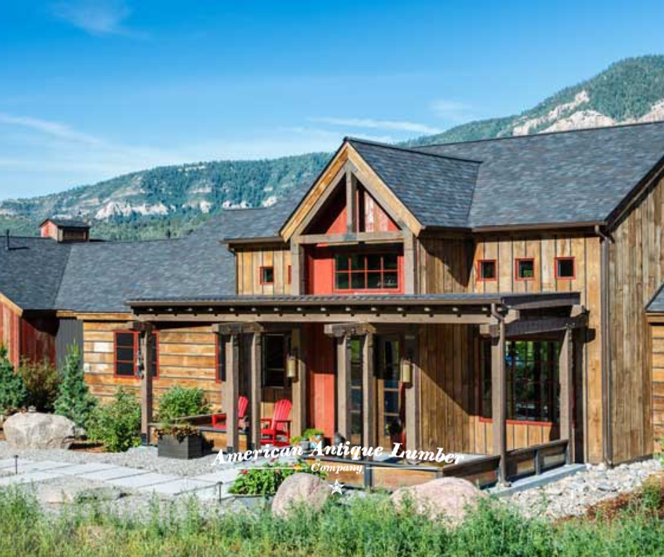Brown reclaimed wood exterior with red window trim and red Adirondack chairs on front porch tree lined red Durango, Colorado cliffs behind. 