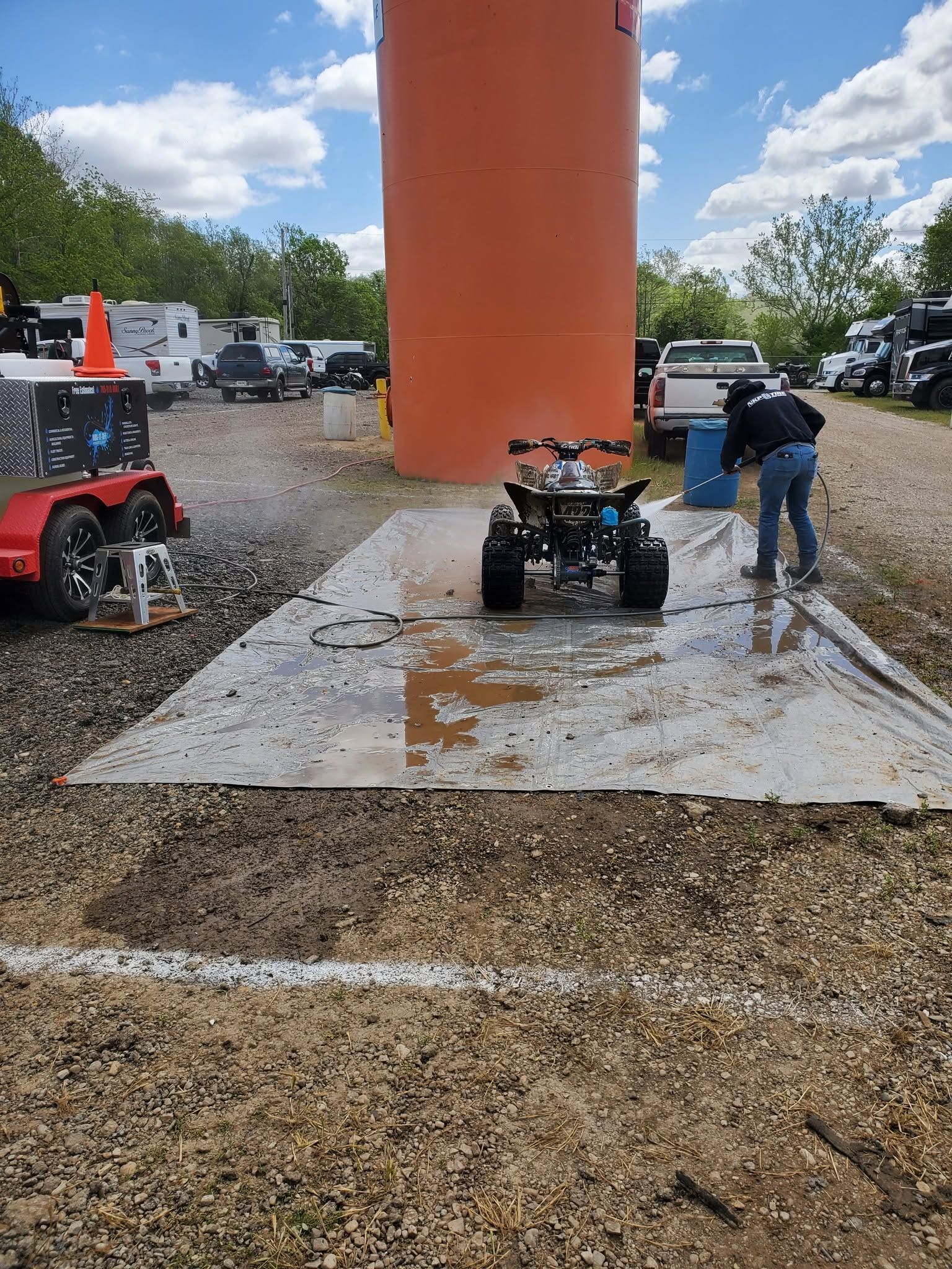 Two people with RC cars on a gravel lot beside a large orange inflatable tower
