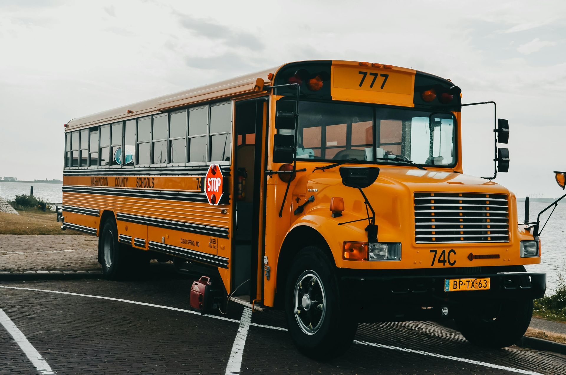 Yellow school bus parked on a road, front view, with route number 777 displayed.