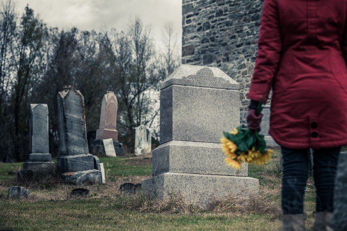 woman standing In front of grave