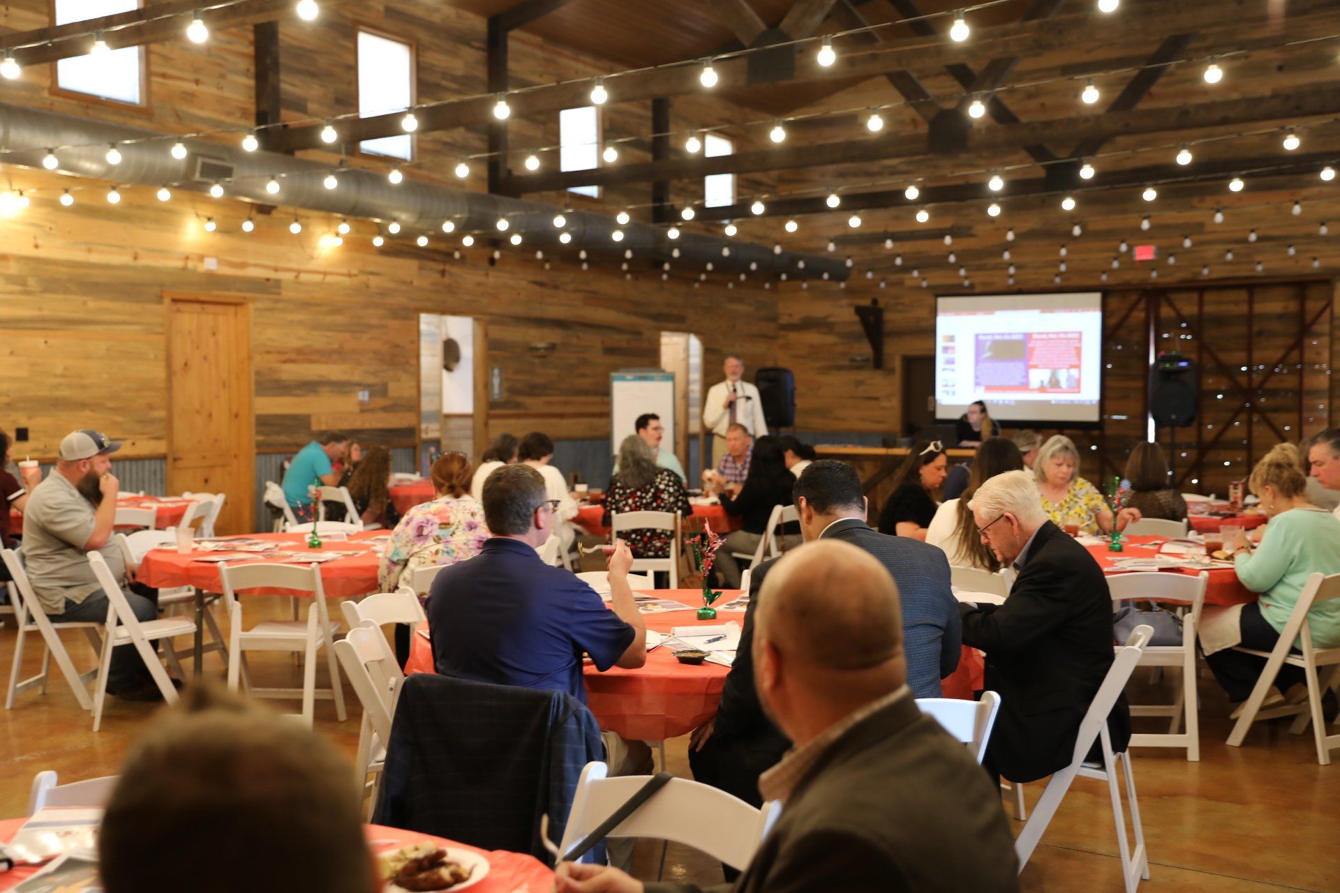 A group of people are sitting at tables in a large room.