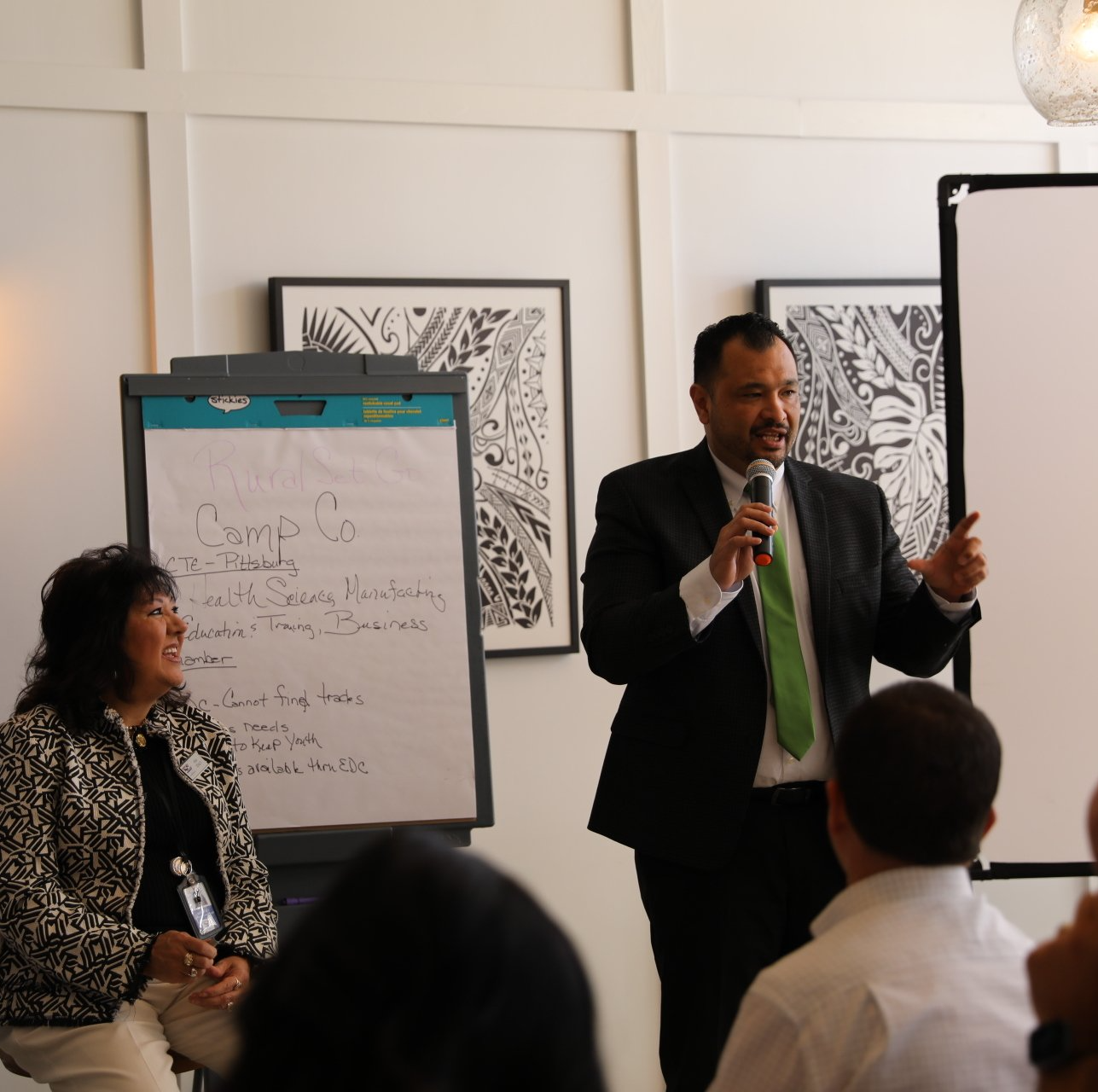 A man in a suit is giving a presentation to a group of people