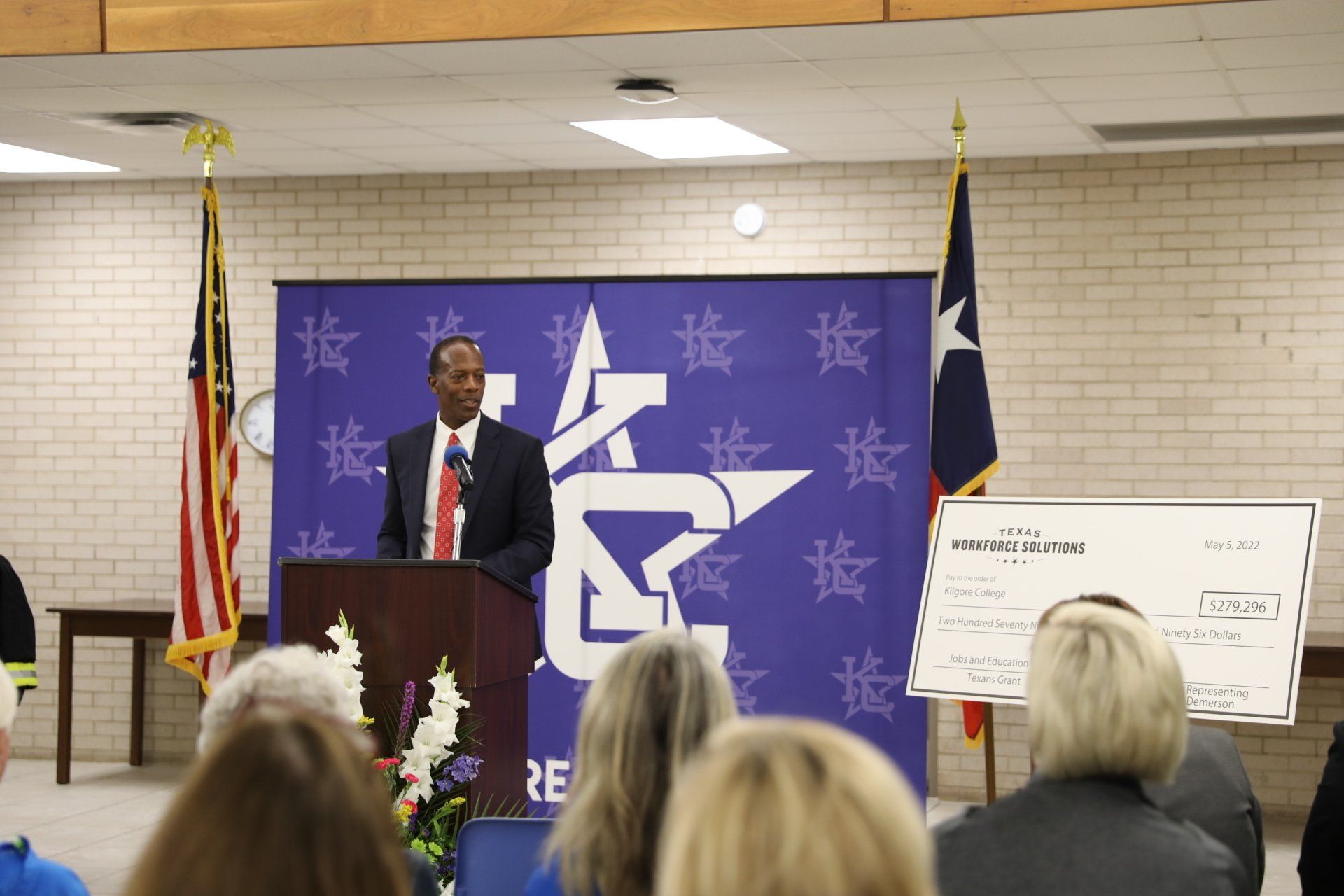 A man stands at a podium giving a speech to a group of people