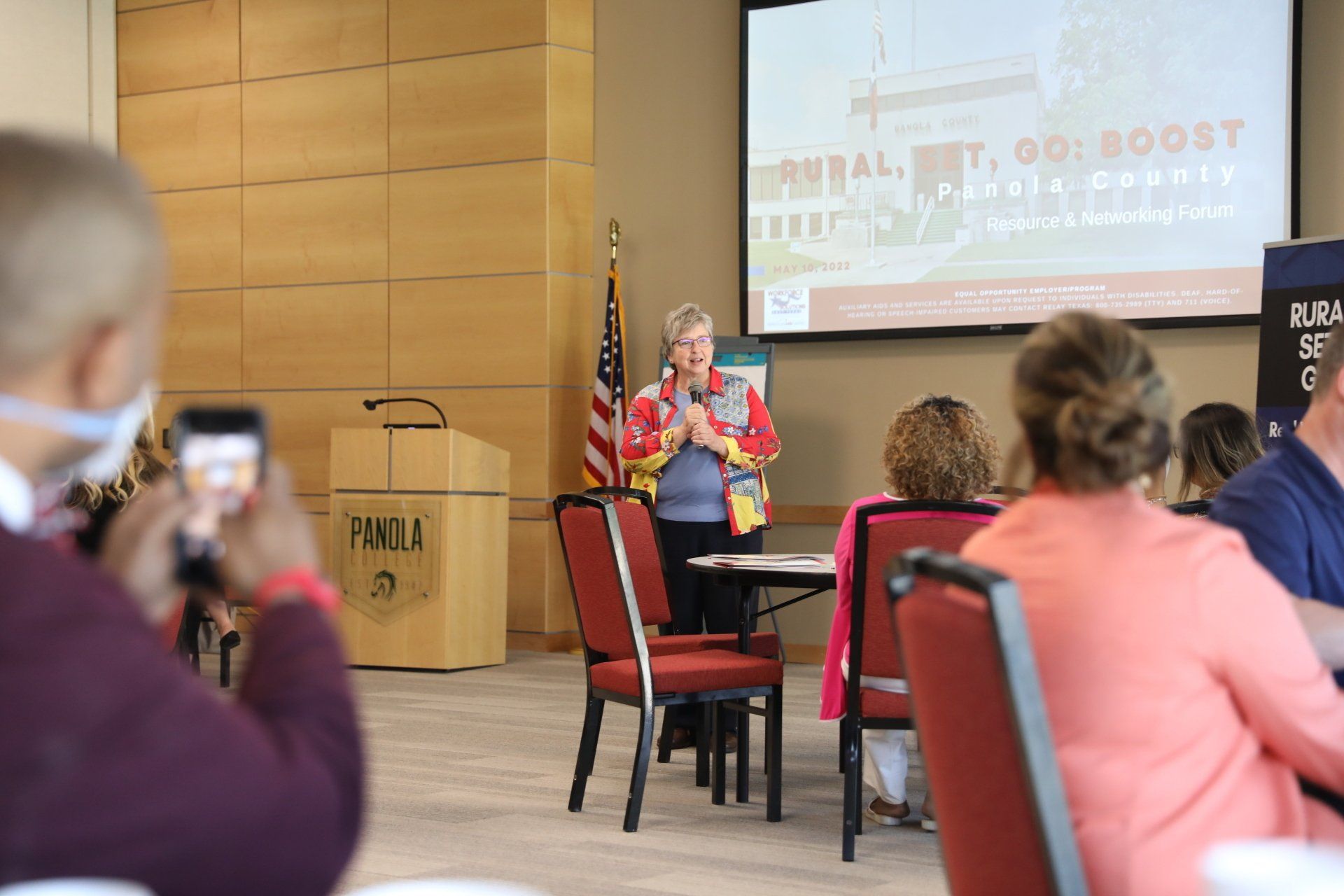A woman is giving a presentation to a group of people in a room.