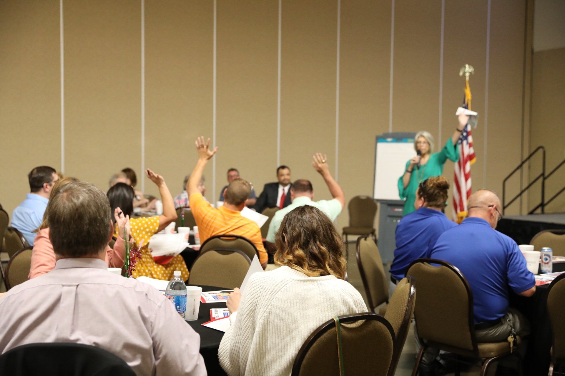 A group of people are sitting in a room with their hands up.