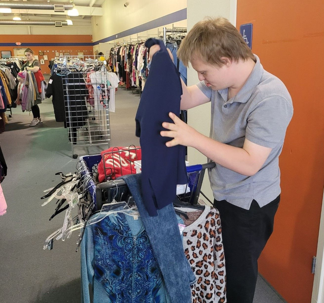 A man is looking at a blue shirt in a store