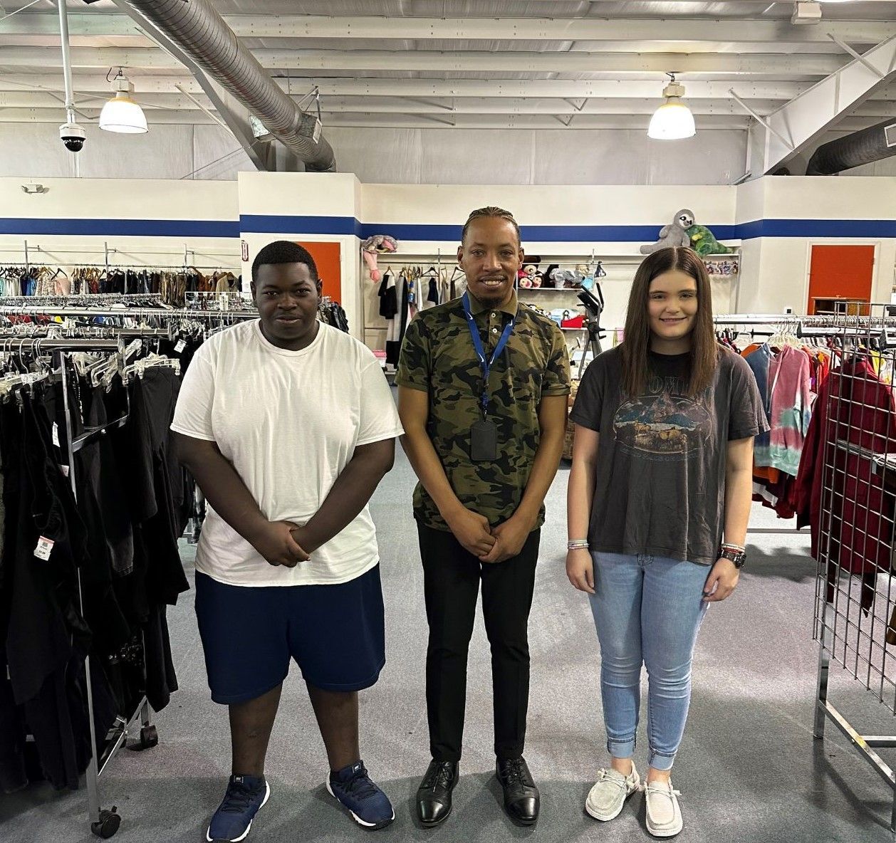 Three people are posing for a picture in a clothing store.
