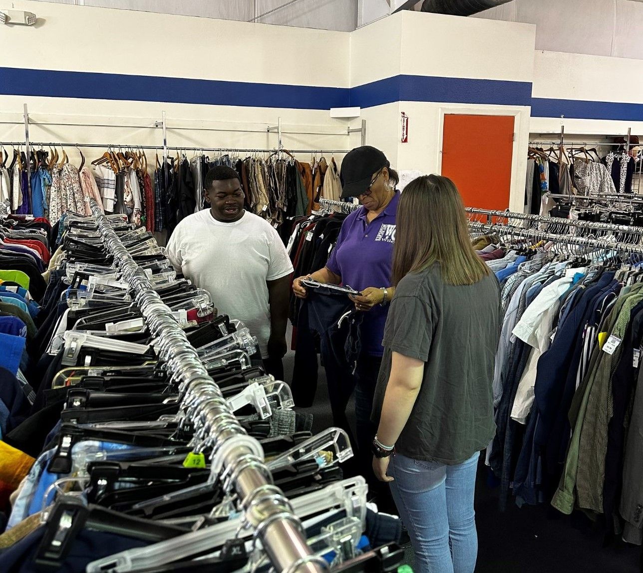 A man and a woman are looking at clothes in a store