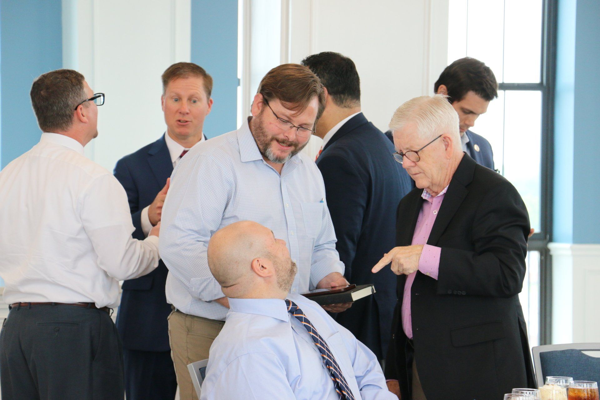 A group of men are standing around a table talking to each other.