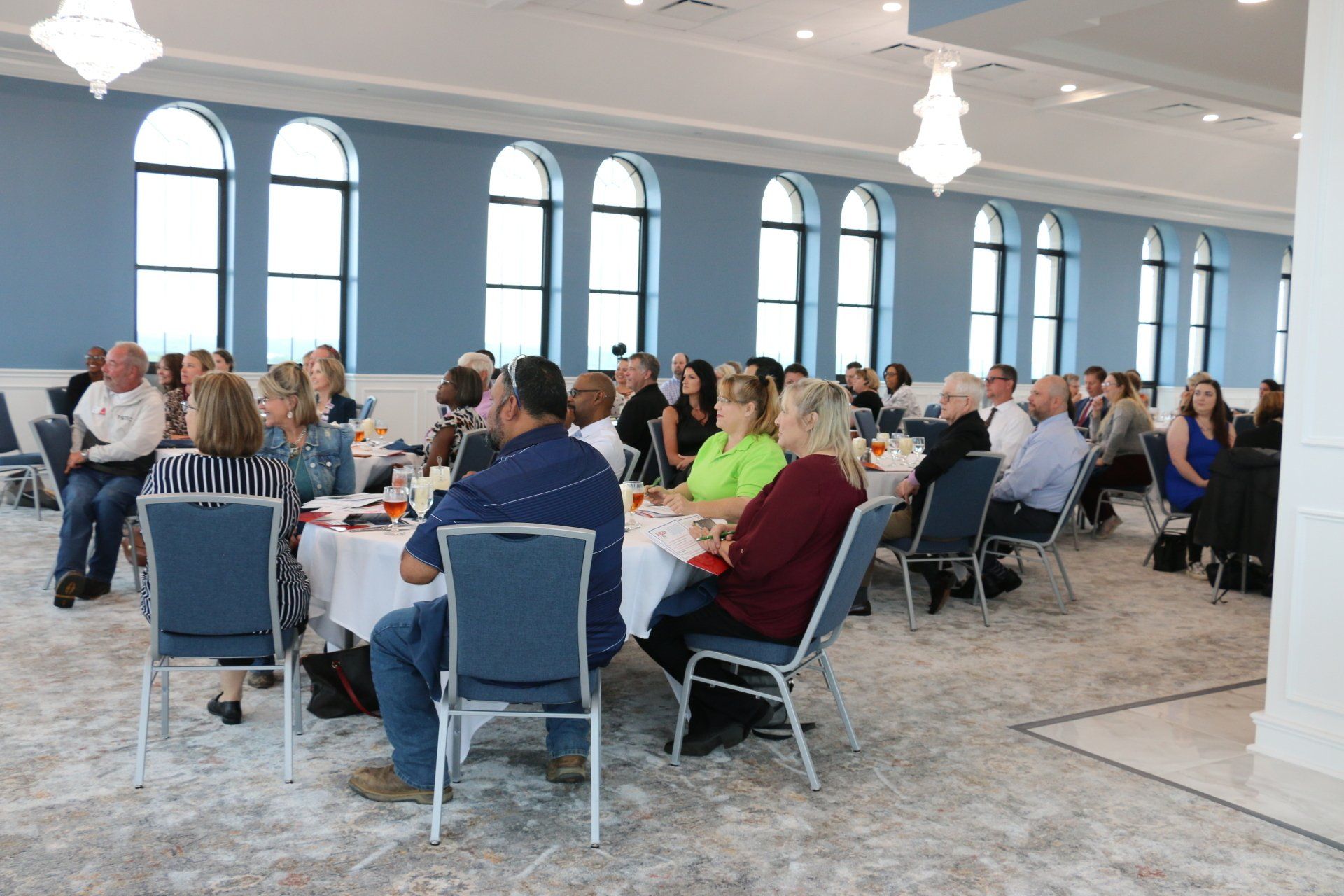 A large group of people are sitting at tables in a large room.