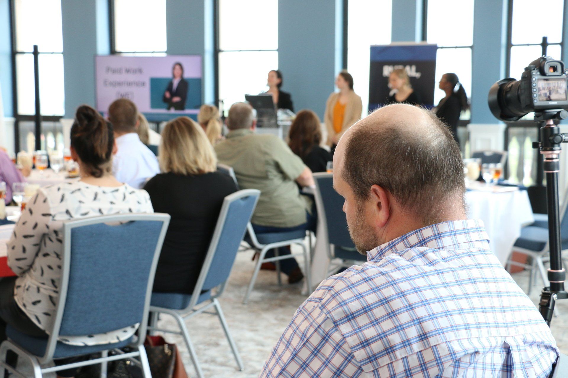 A man is sitting in front of a group of people at a conference.