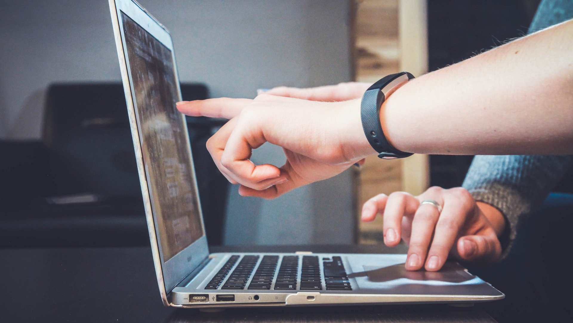 A person is pointing at something on a laptop computer.