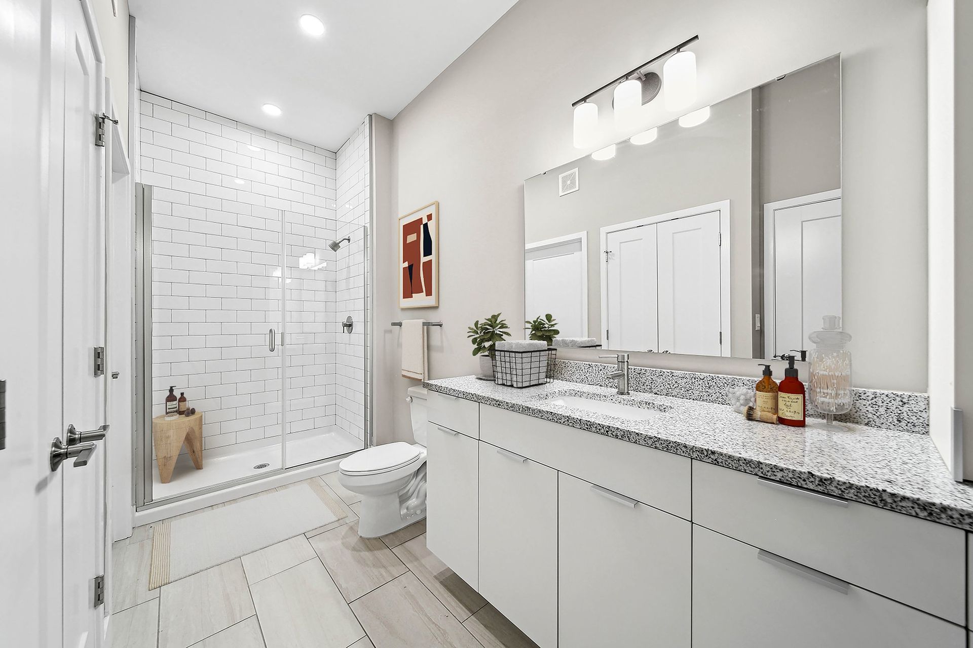 Modern bathroom with glass-enclosed shower, white subway tiles, and a granite countertop vanity at Chroma, offers apartments in downtown STL.