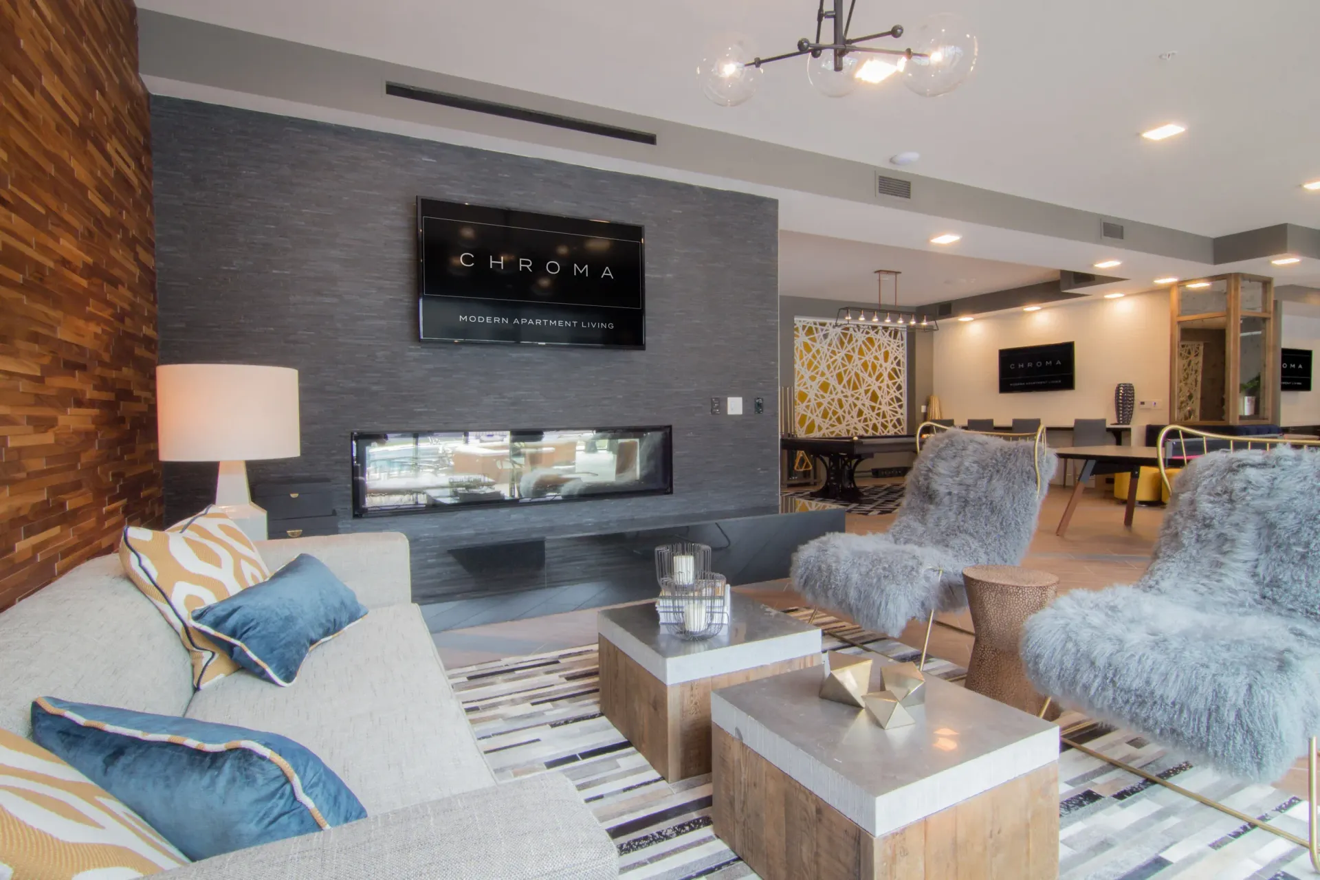 Modern community lounge with a fireplace, sofa seating, and plush chairs at Chroma, offers apartments in The Grove.