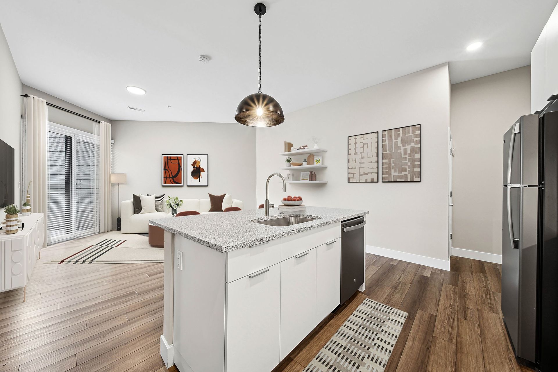 Open-concept kitchen with island, granite countertop, and stainless steel appliances at Chroma, offers apartments in The Grove STL.