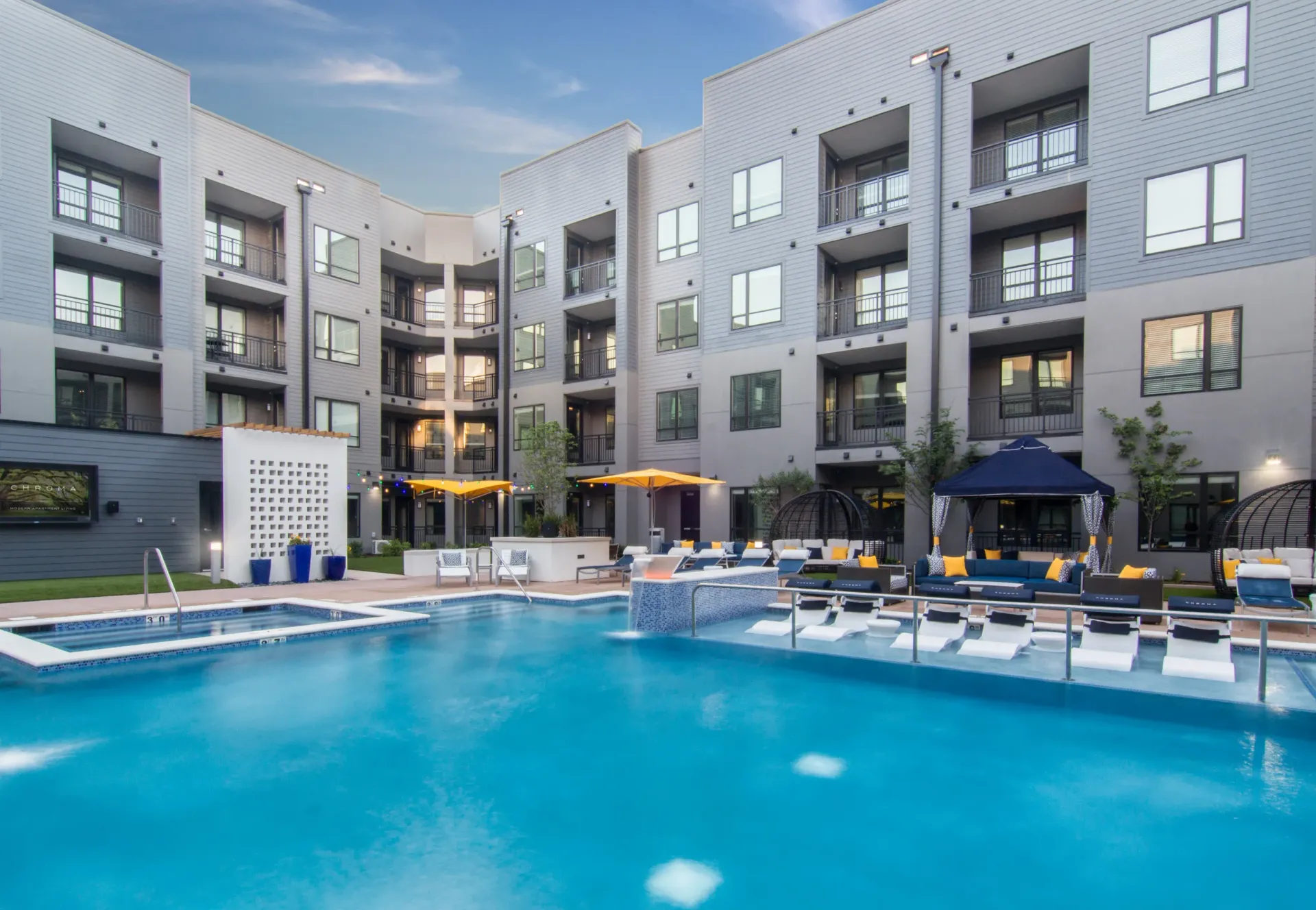 The pool area at Chroma features lounge seating and is surrounded by modern apartment buildings around a courtyard. Apartments are available for rent in St. Louis.