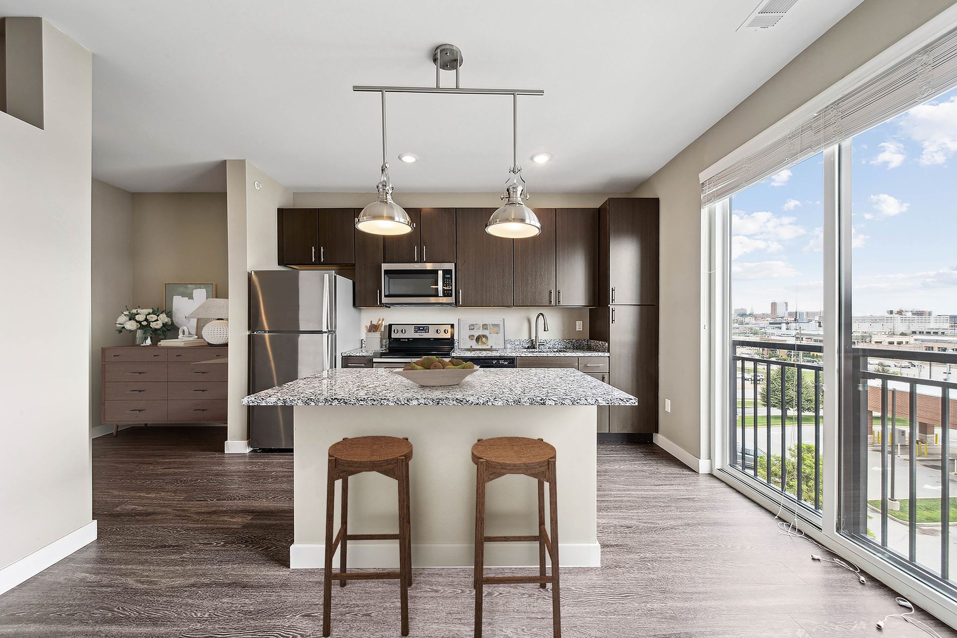 Modern apartment kitchen with granite island, stainless appliances, dark cabinets, and large balcony windows at Chroma, offers apartments in Downtown STL.