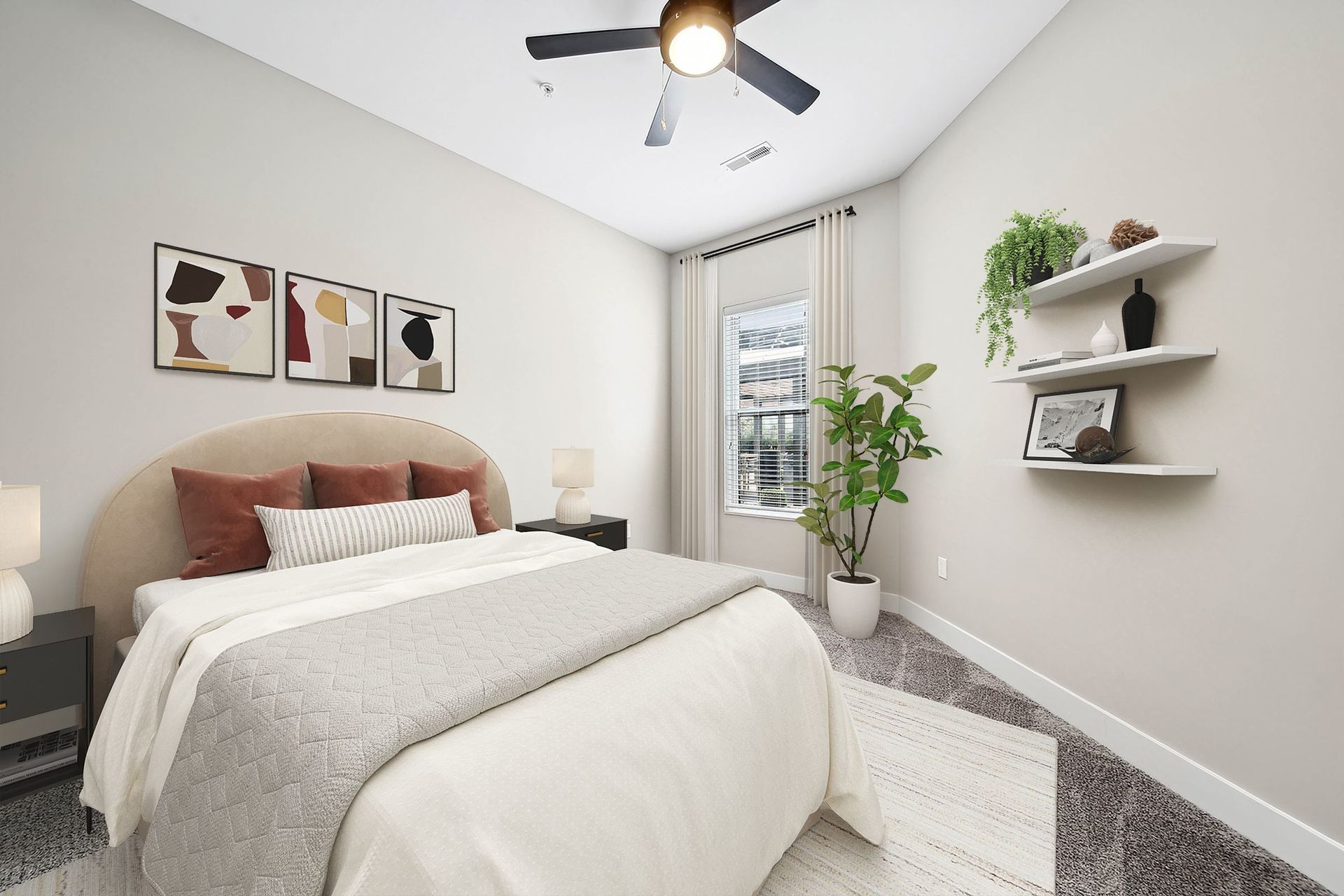 Bedroom in a modern apartment with a beige upholstered bed, abstract art above, and a ceiling fan at Chroma, offers St Louis apartments in MO.