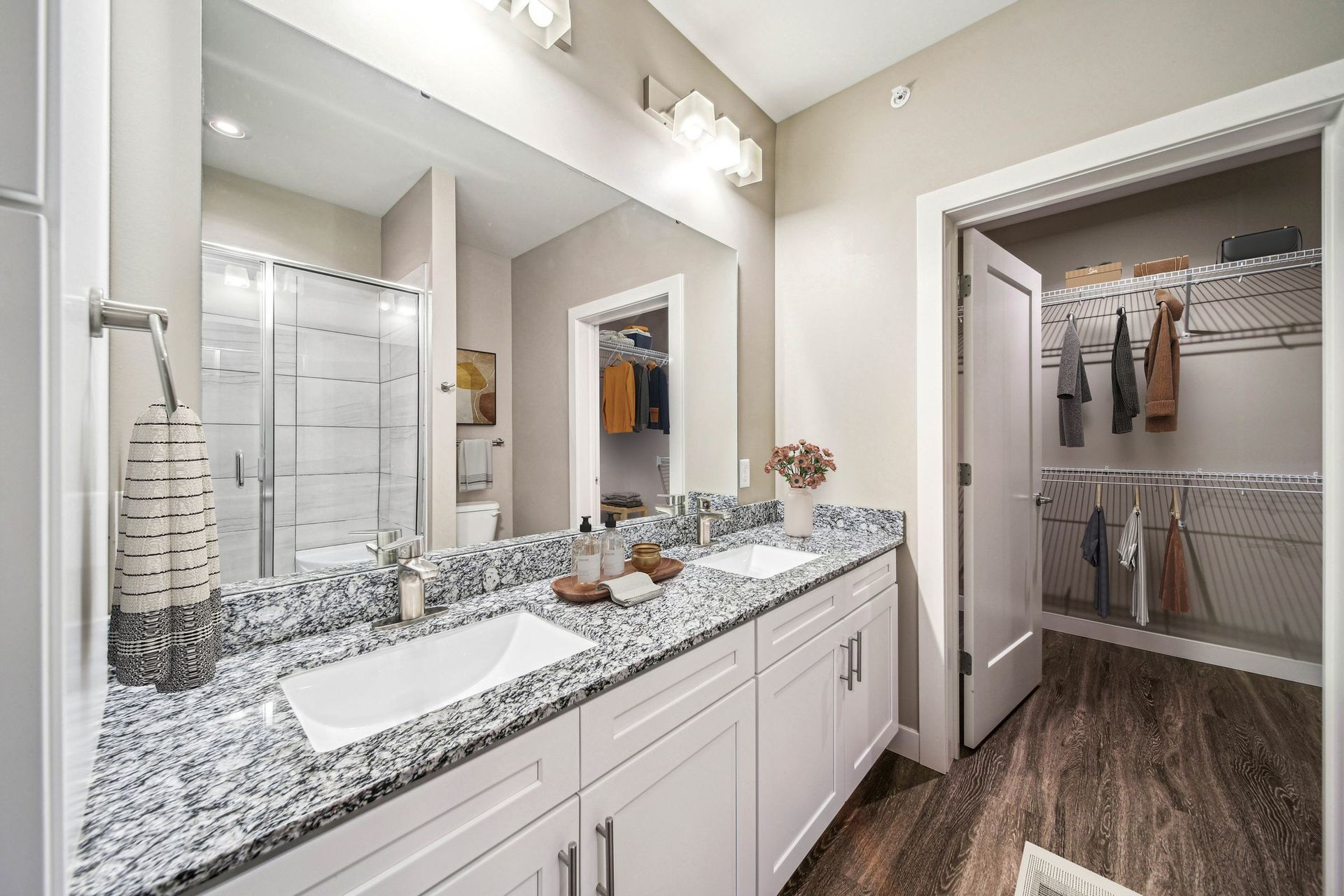 Dual-sink bathroom vanity with granite counter, large mirror, and walk-in closet at Chroma, offers apartments for rent in St Louis, MO.