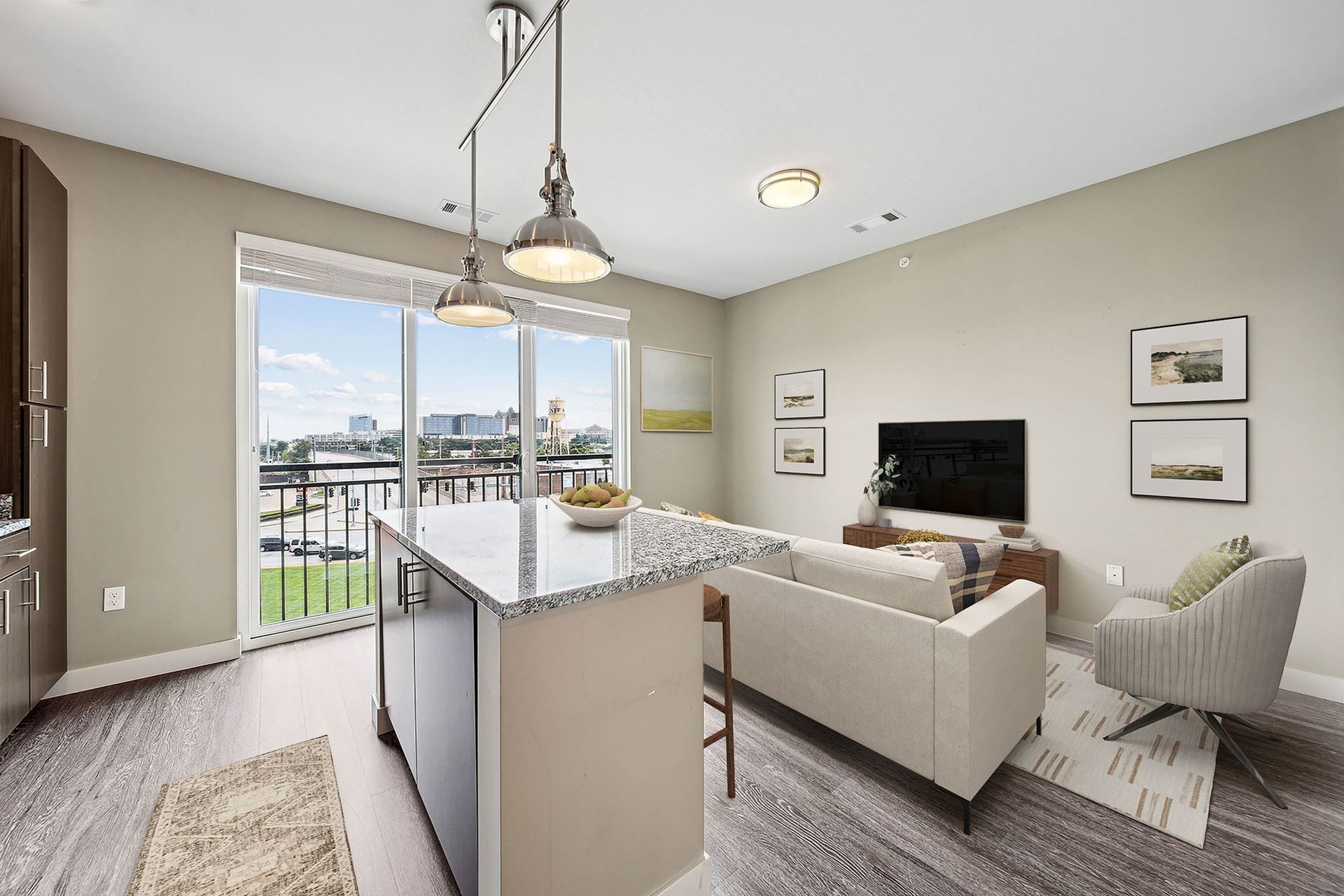 Open-concept living area in a modern apartment with a granite island, sofa, and large balcony windows at Chroma, offers luxury apartments Saint Louis.