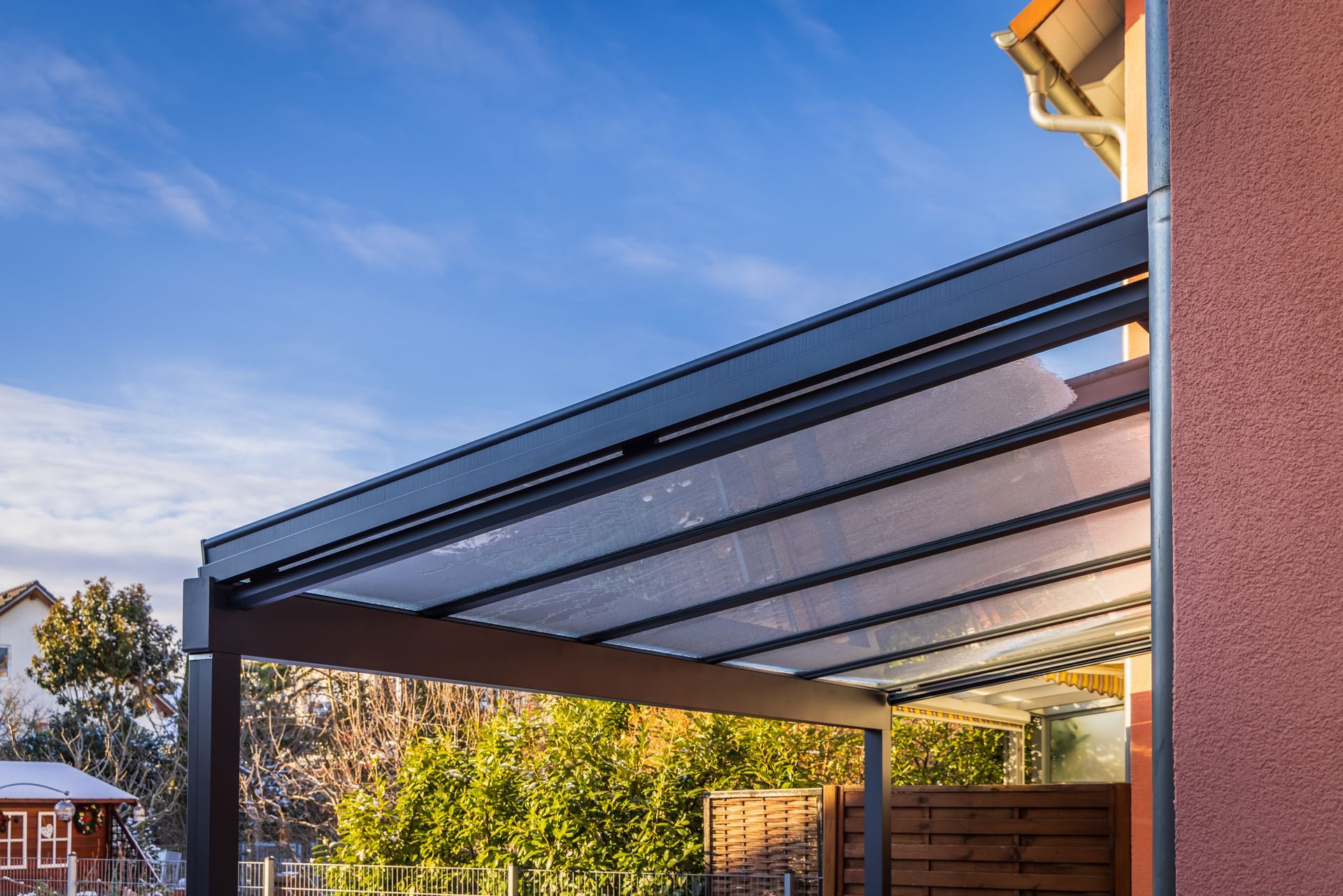 Retractable patio awning extended over a backyard deck beside a house at sunset Retractable patio awning extended over a backyard deck beside a house at sunset