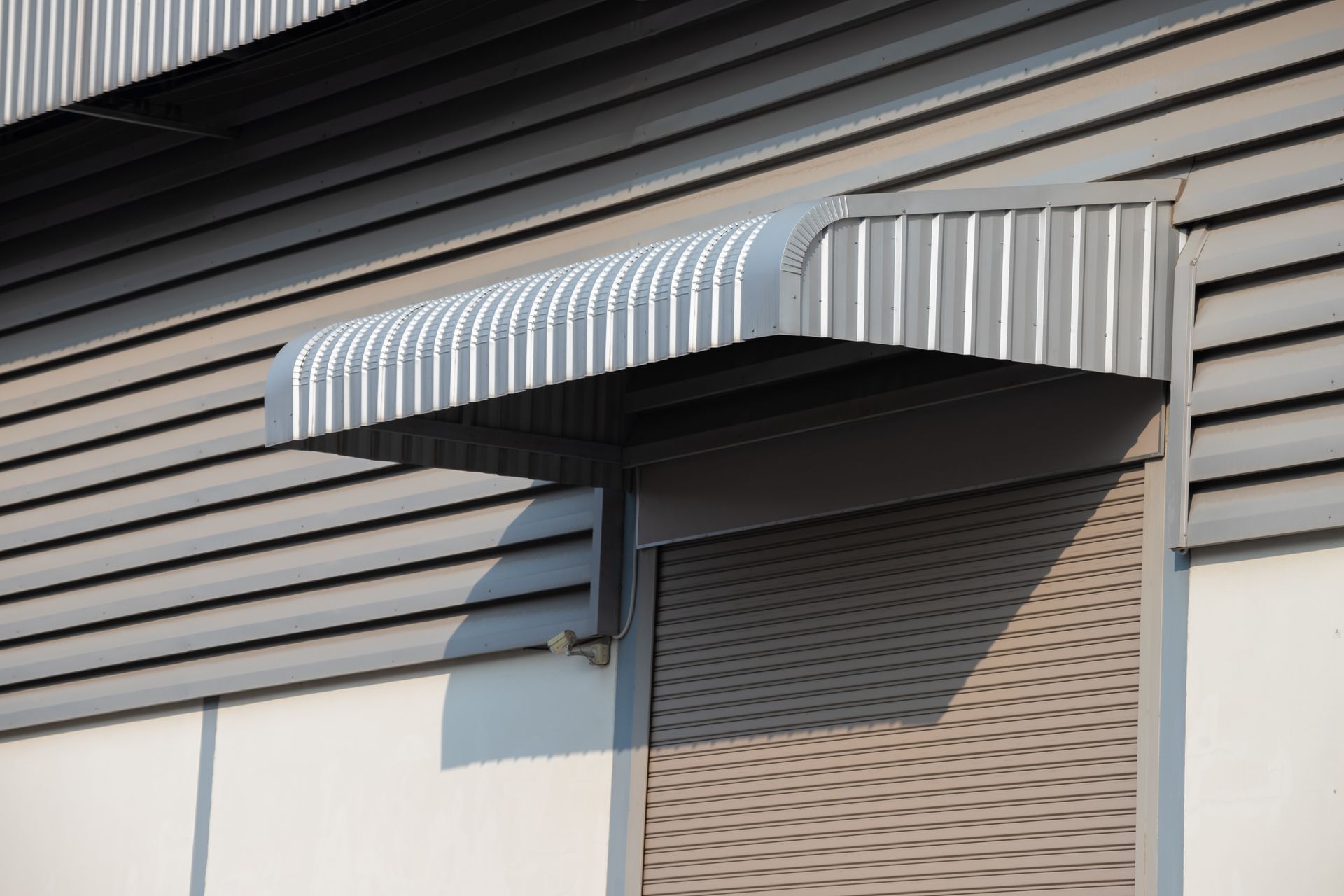Striped metal awning over a doorway on a modern building exterior Striped metal awning over a doorway on a modern building exterior