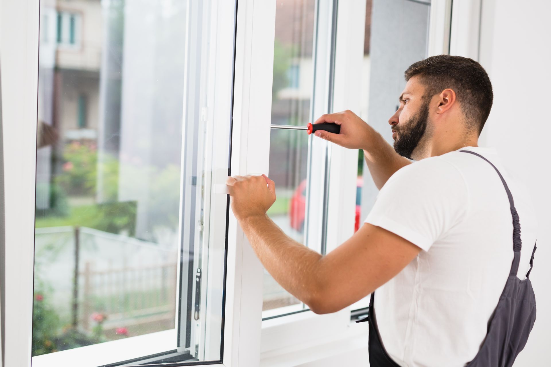 Worker adjusting a window frame with a tool in a bright room Worker adjusting a window frame with a tool in a bright room