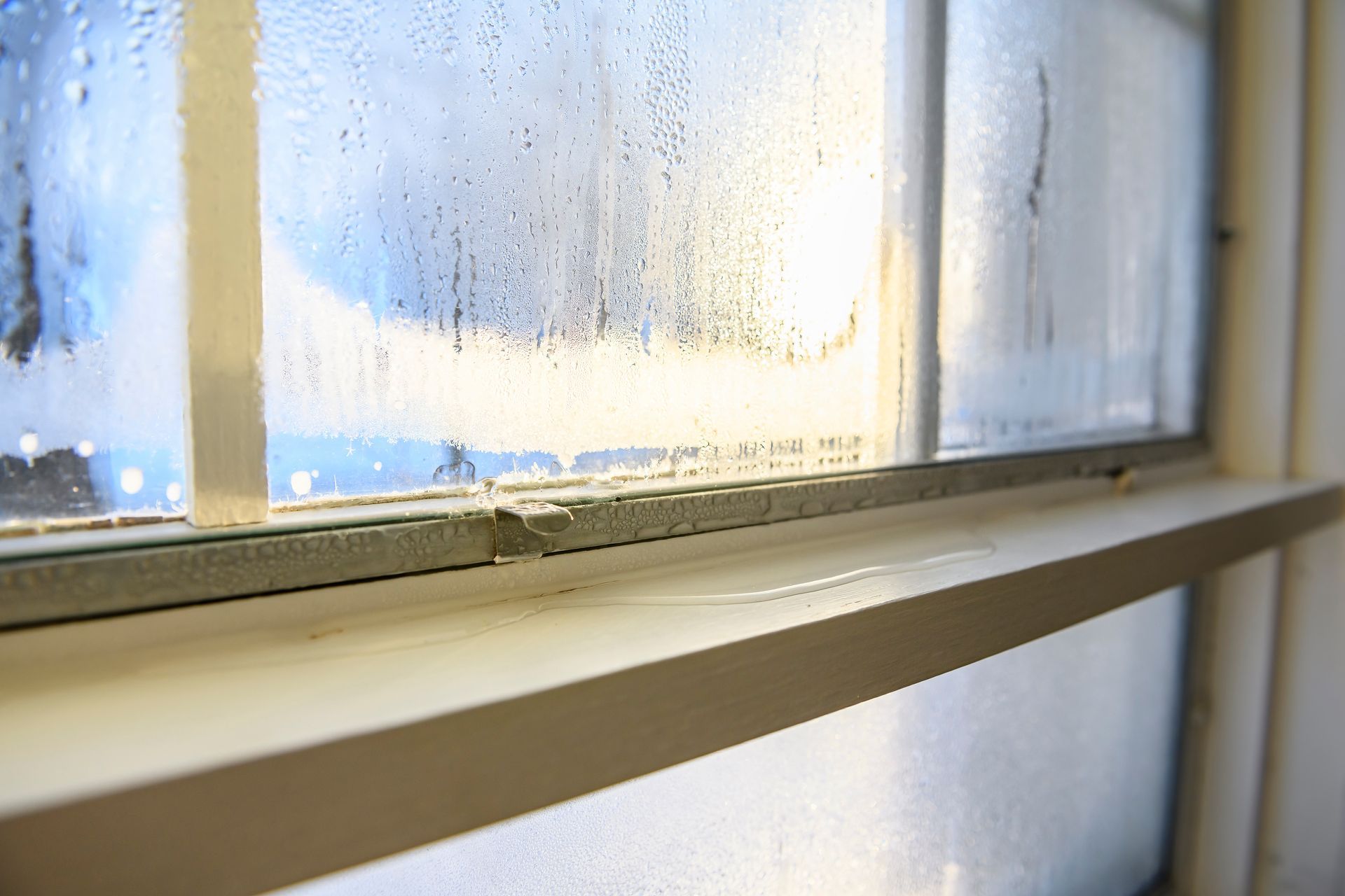 Rain-speckled window with a white sill and soft sunlight streaming in Rain-speckled window with a white sill and soft sunlight streaming in