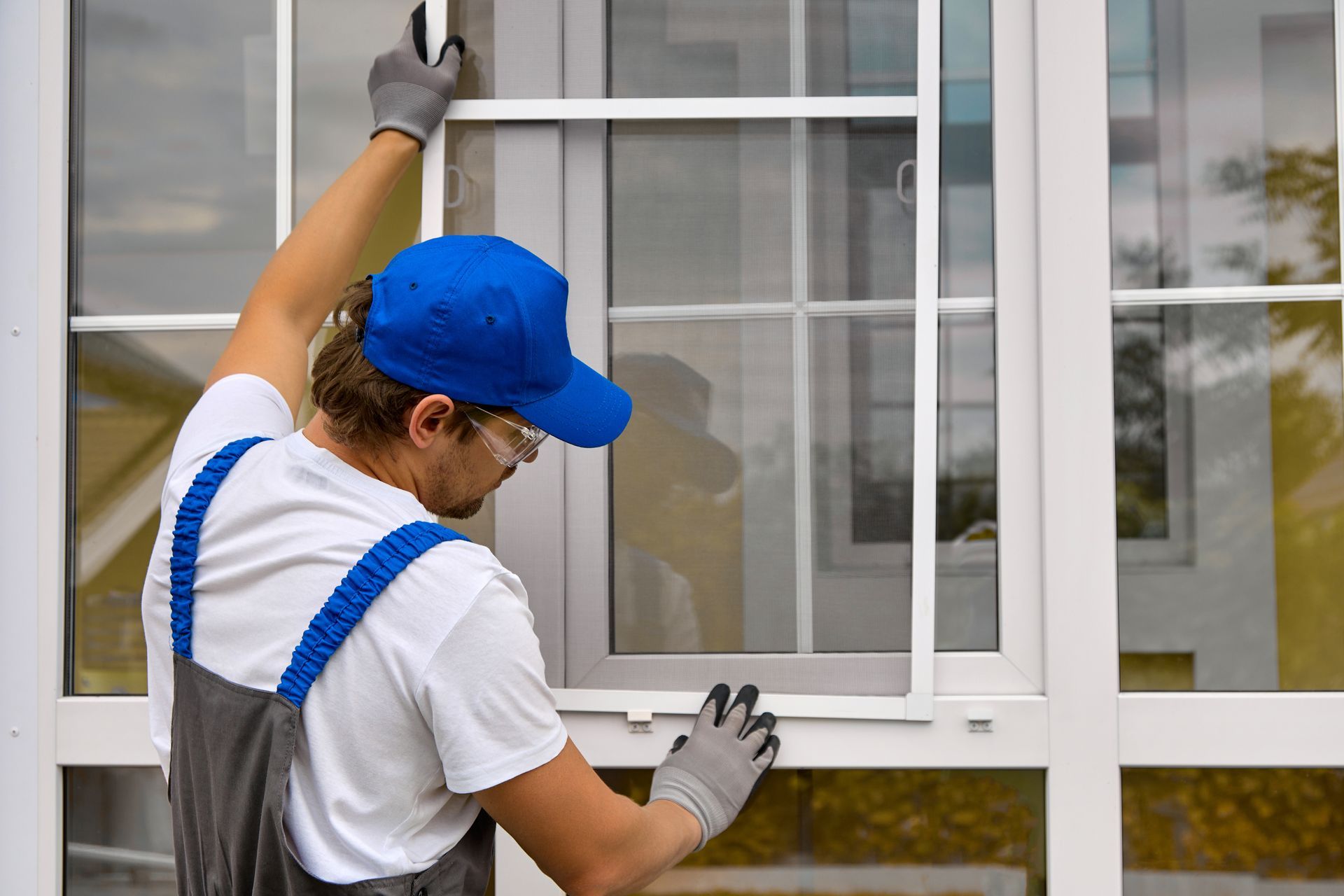 Window cleaner in blue cap washing a house window with a squeegee Window cleaner in blue cap washing a house window with a squeegee