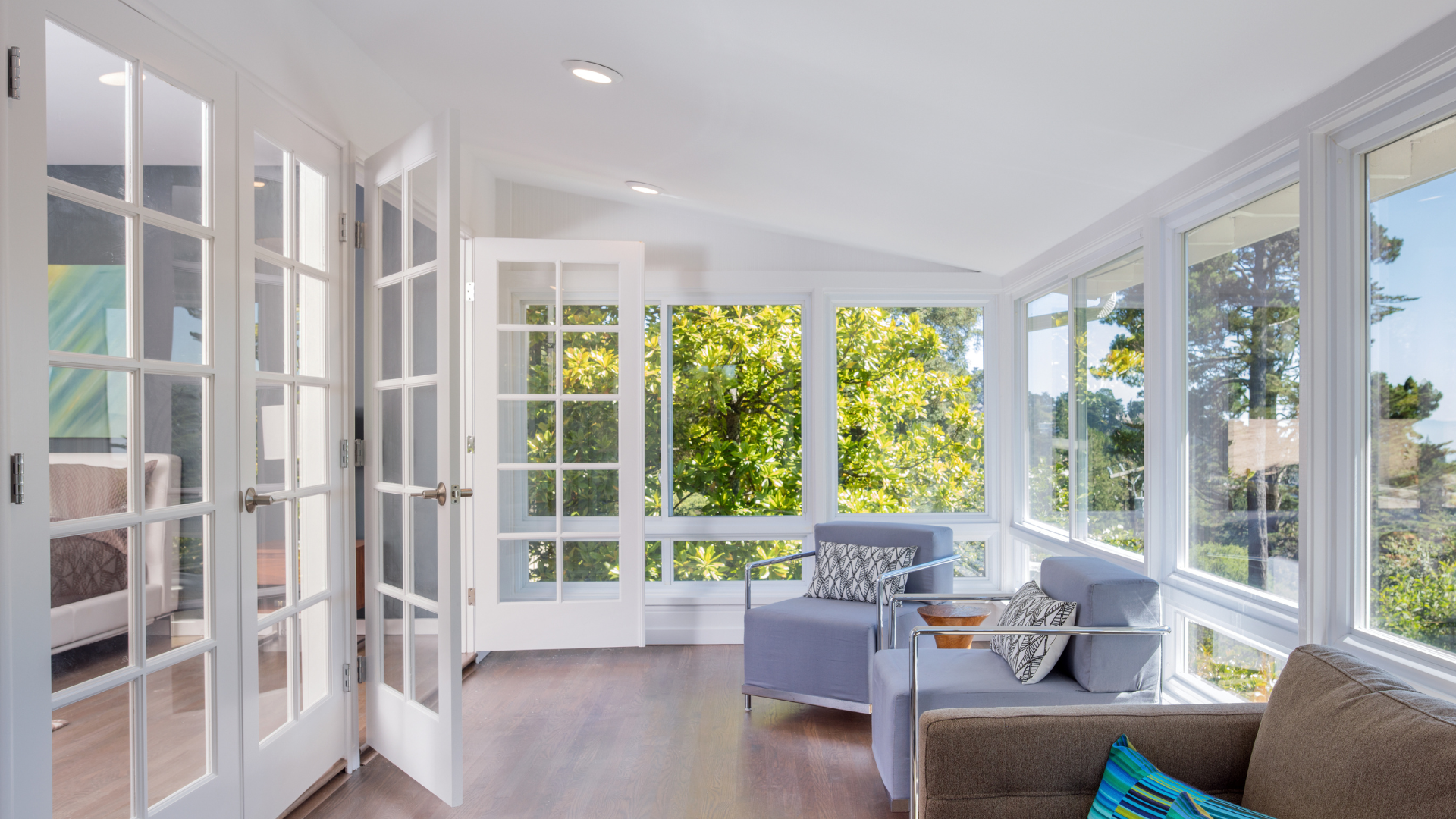 a living room with a couch , chair , and lots of windows .