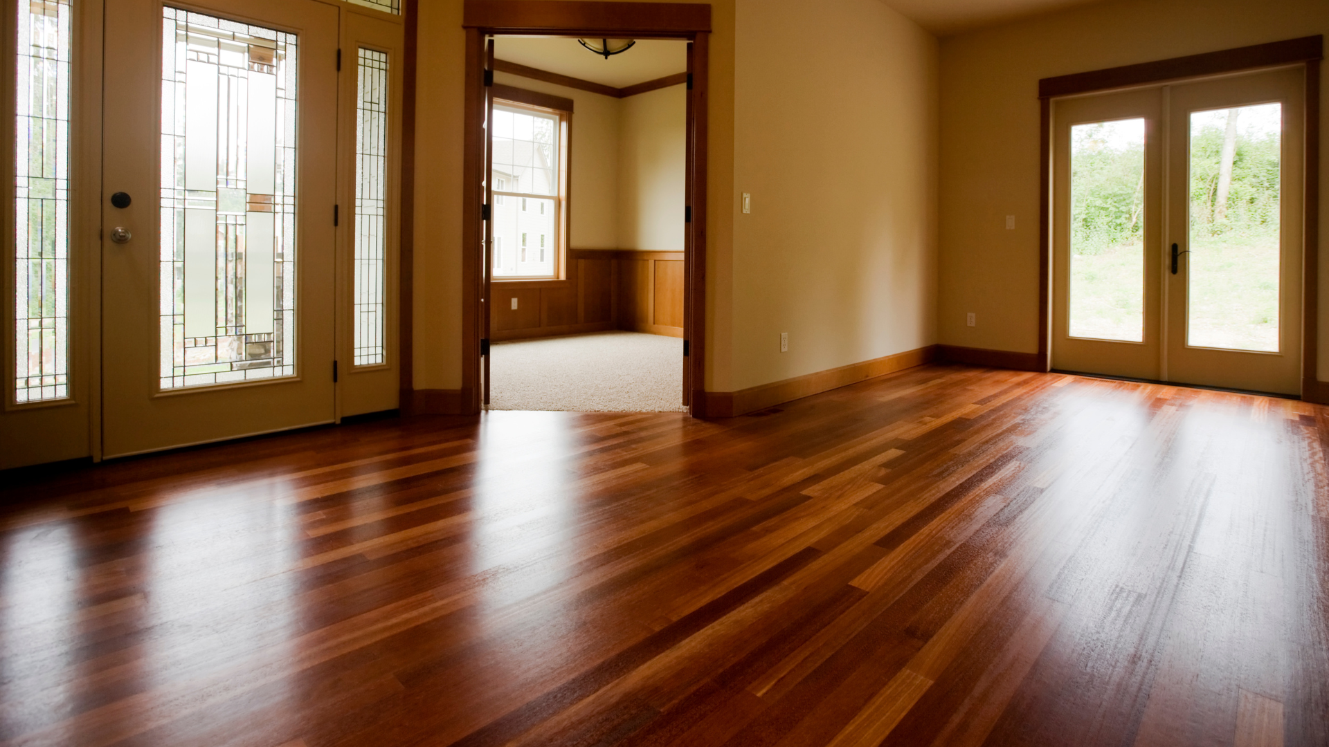 an empty living room with hardwood floors and stained glass doors .