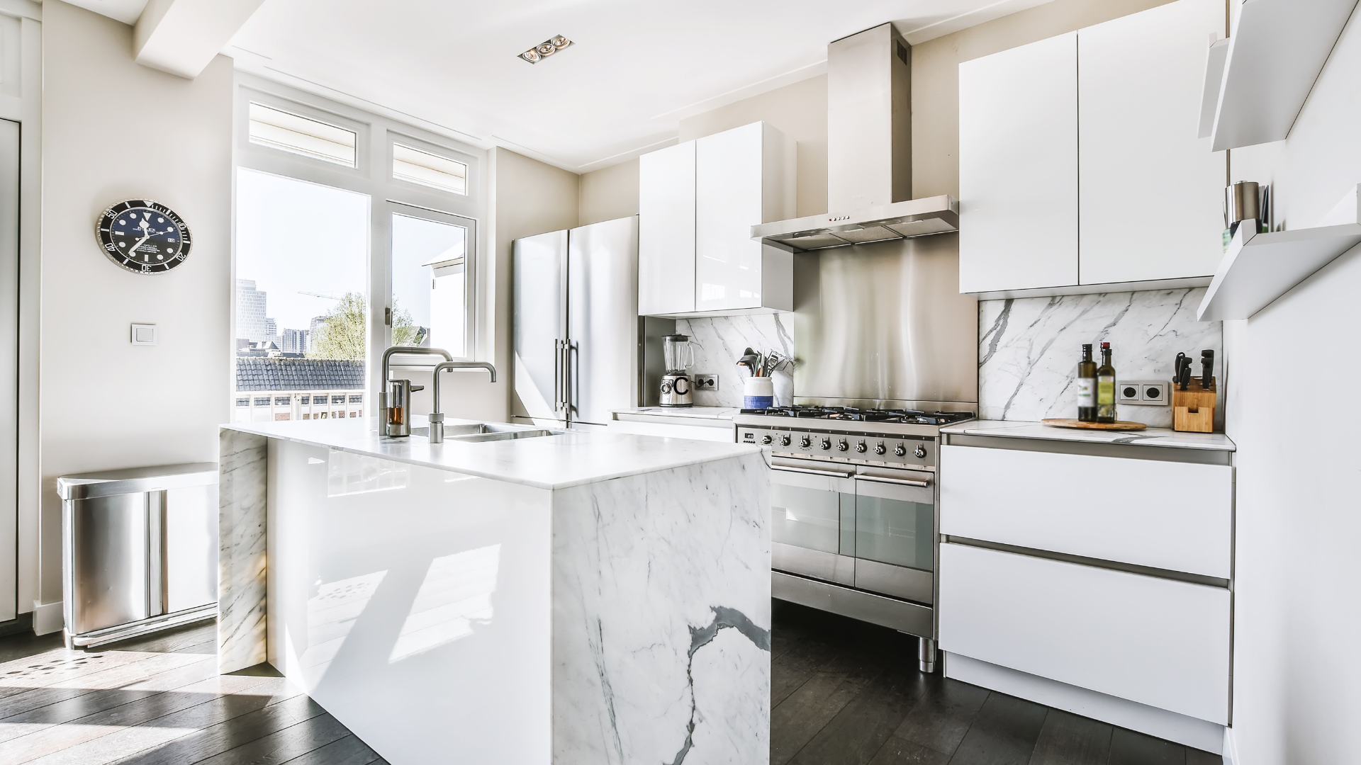 a kitchen with white cabinets , stainless steel appliances , and a large island .