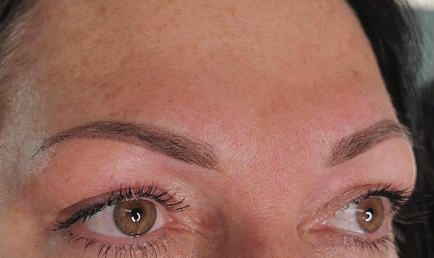 A close up of a woman 's face with brown eyes and eyebrows.