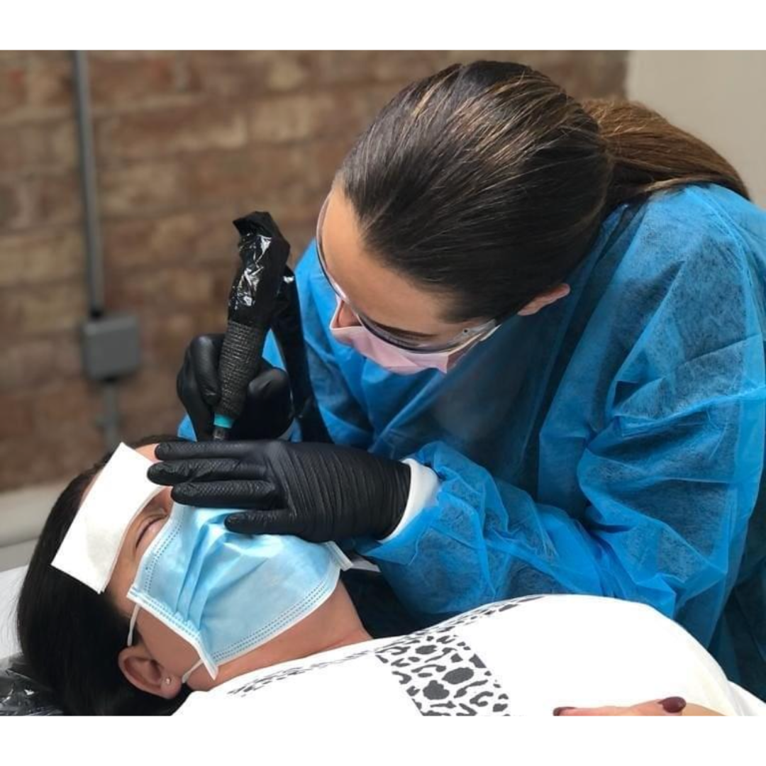 A woman wearing a mask and gloves is working on a patient 's eyebrows