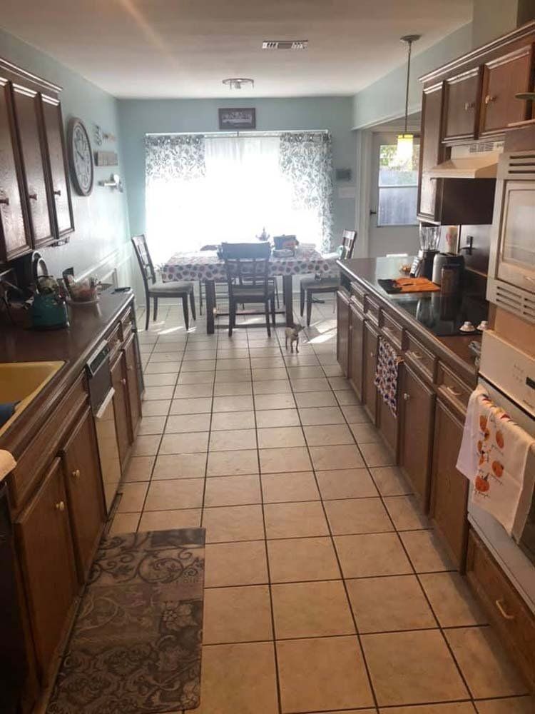 A kitchen with a dining room table and chairs in the background.