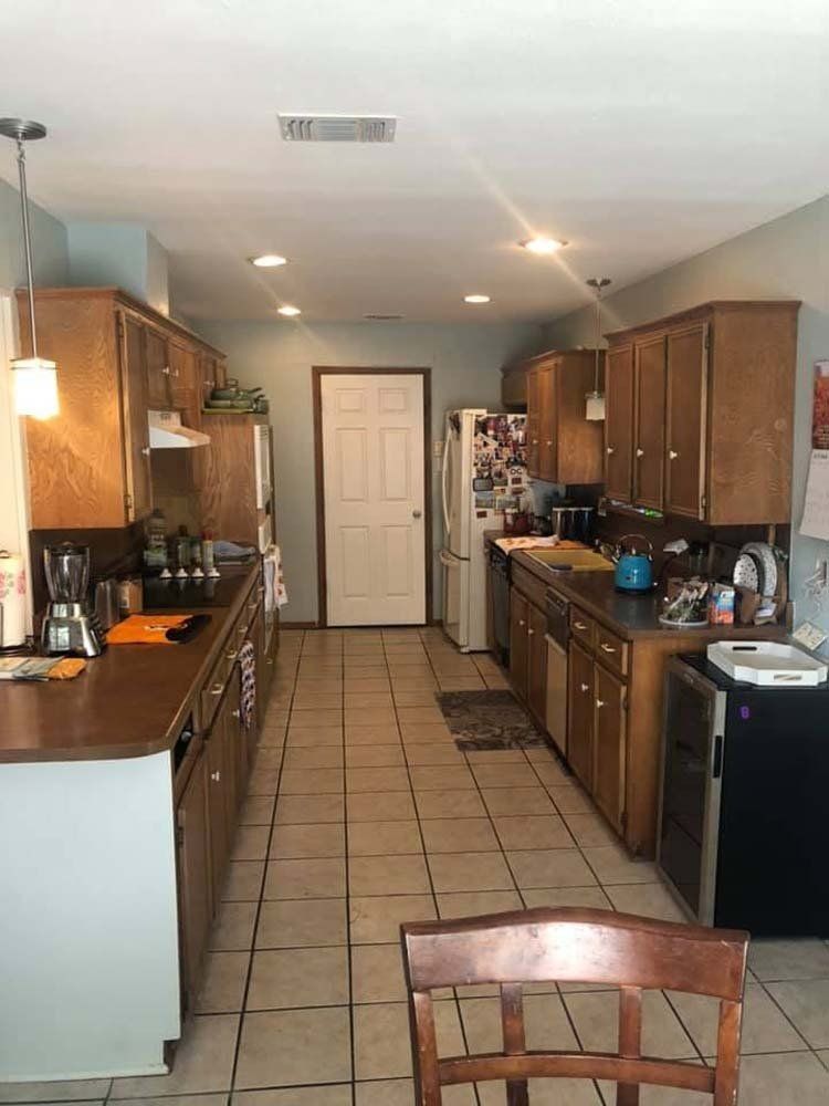A long kitchen with wooden cabinets and tile floors