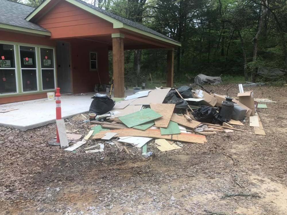 A pile of trash is in front of a house under construction.