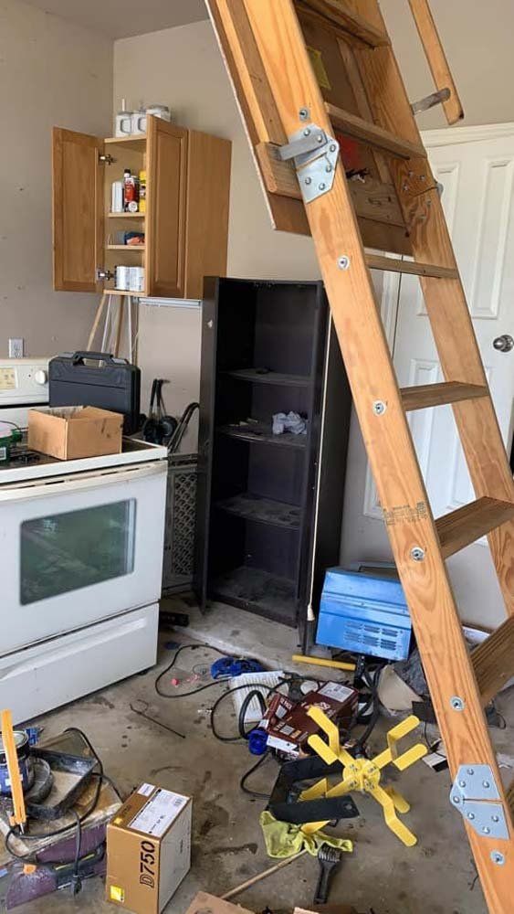 A messy kitchen with a wooden ladder leading up to the attic.