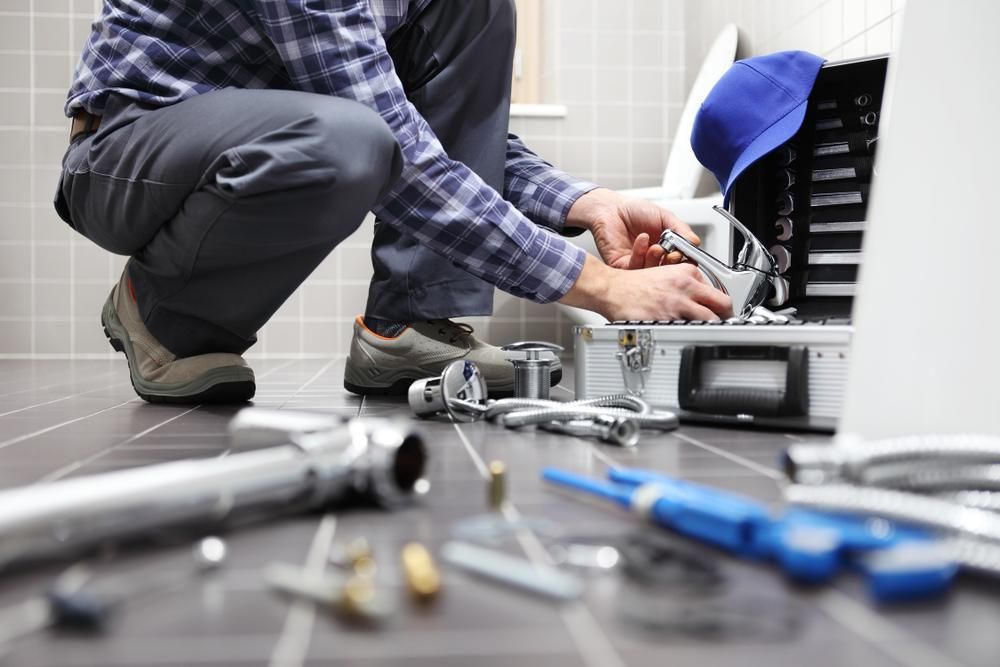 A Plumber Is Working on A Toilet in A Bathroom — ACS Plumbing in Tamworth, NSW