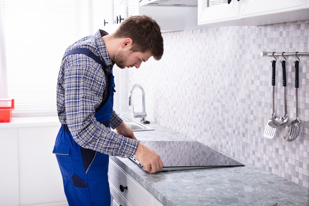 Repairman Installing Induction Stove In Kitchen — Your Local Plumber in Tamworth, NSW