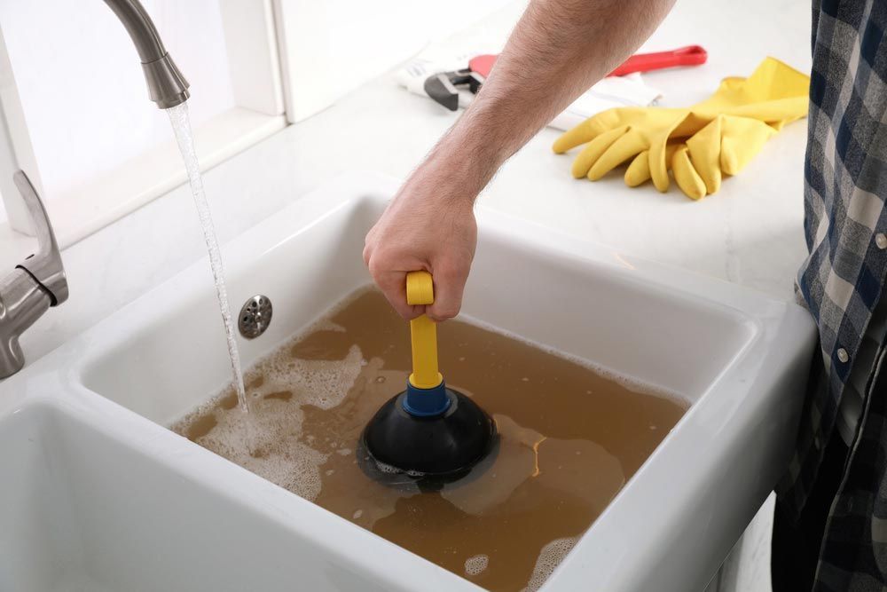 Man Using A Plunger On A Blocked Sink Drain