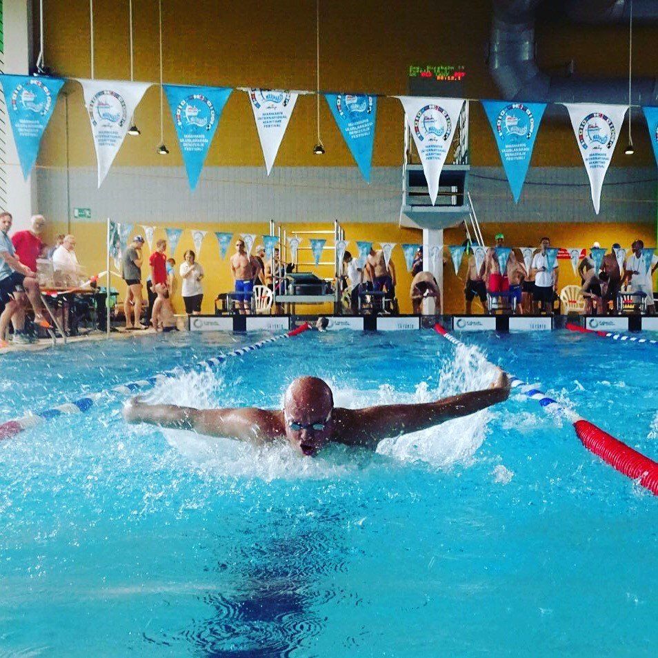 Ein Mann schwimmt in einem Pool, an dessen Wimpel Flaggen hängen