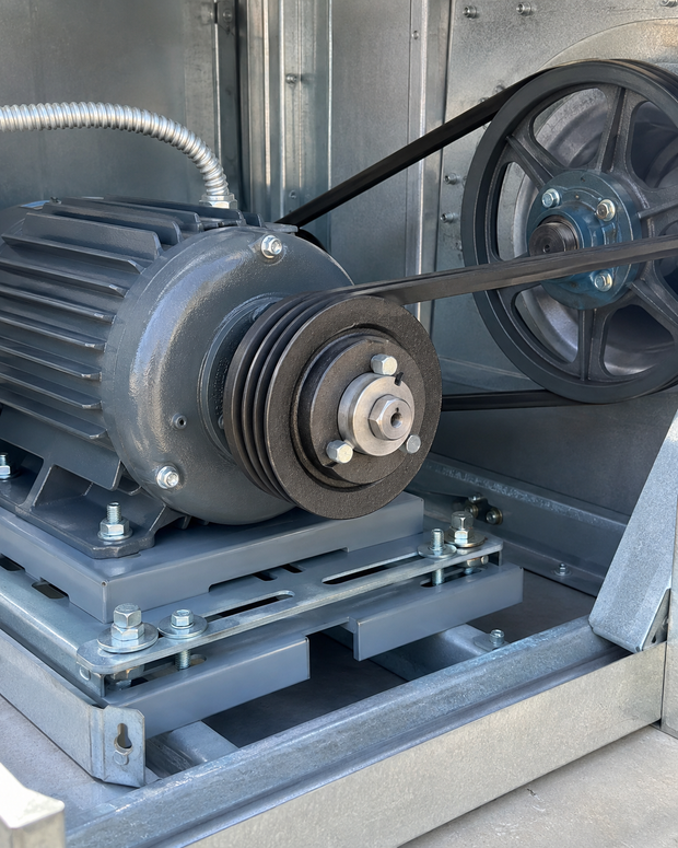 Industrial motor with belt drive and pulleys mounted on a metal base inside a machine enclosure